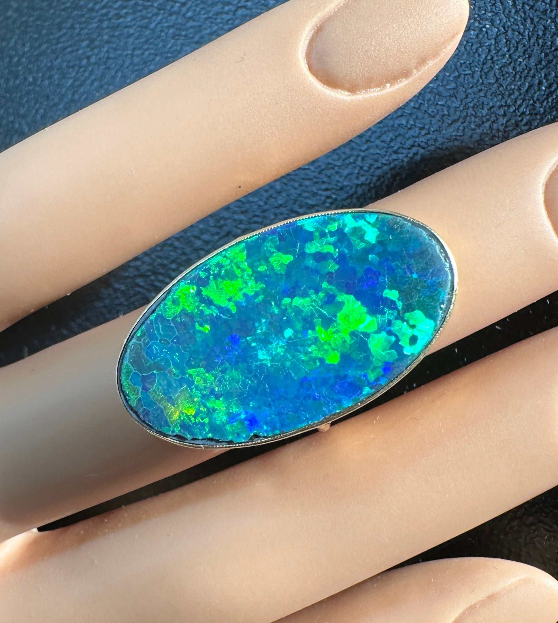 Indulge in a stunning Black Opal Antique Art Deco ring with a gorgeous 13.5 Carat Black Opal with radiant fire set in a 14 Karat Gold setting of great beauty.  The spectacular oval opal flat cut gem is 28mm long, over an inch, and it has some of the