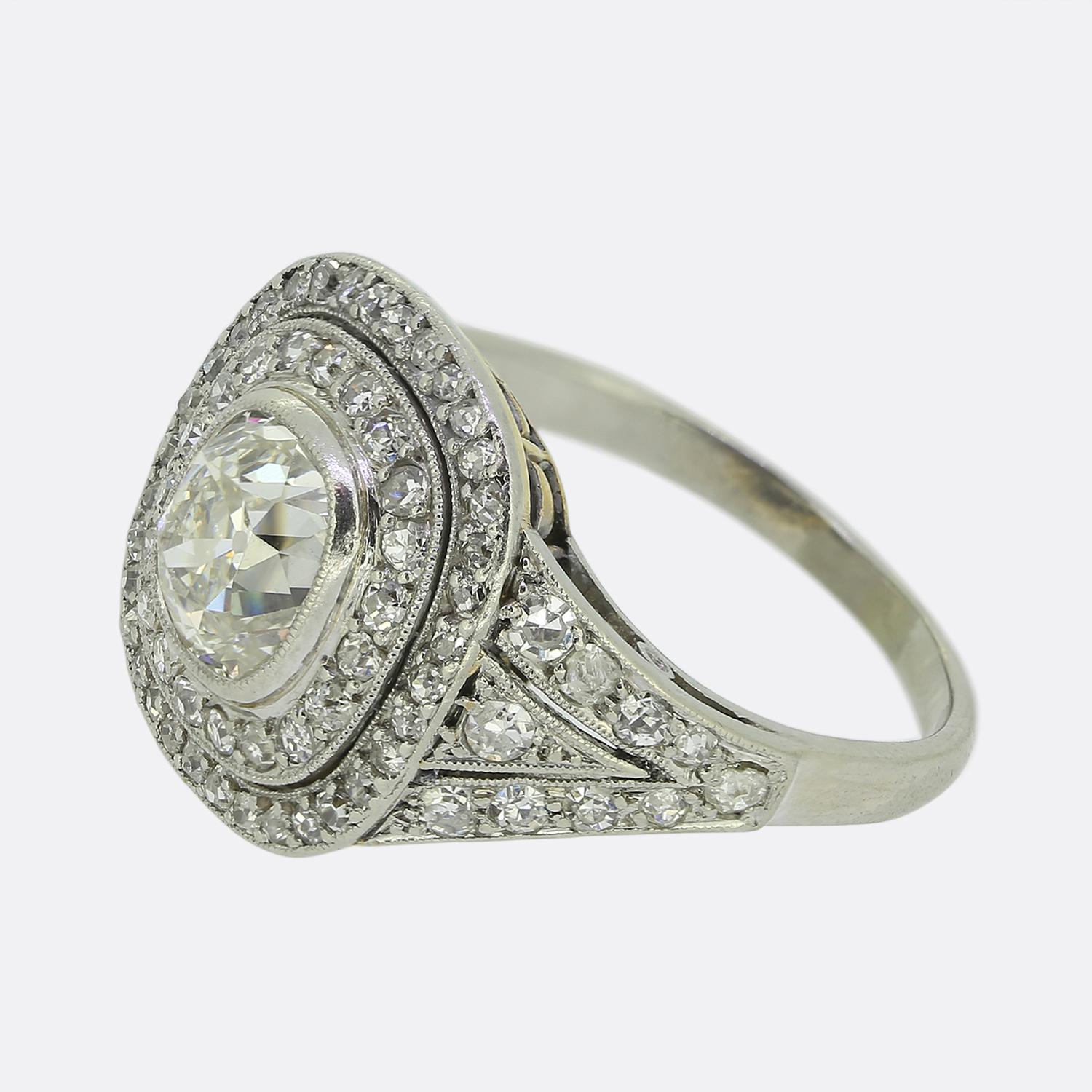 Hier haben wir einen herausragenden Clusterring aus der Zeit des Art déco. Dieses raffinierte Schmuckstück aus 18-karätigem Gold ist mit einem großen Diamanten im Minenschliff in der Mitte der Vorderseite versehen. Dieser Hauptstein ist von einem