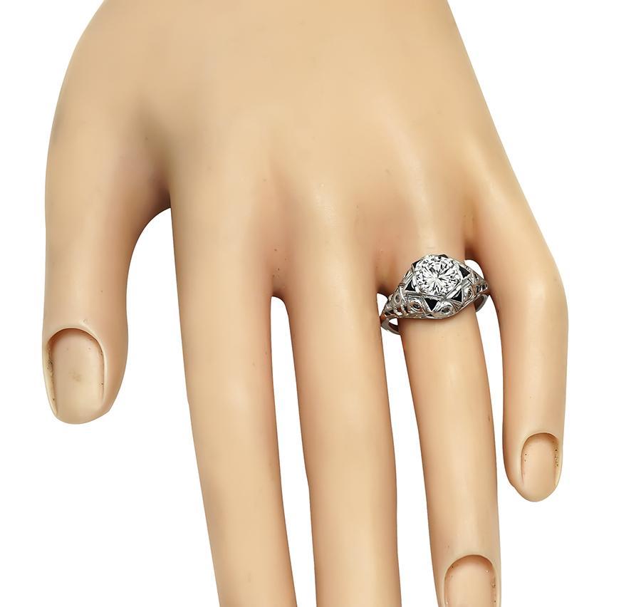 This is a charming platinum engagement ring from the Art Deco era. The ring is centered with sparkling round cut diamond that weighs approximately 1.30ct. The color of the diamond is J-K and the clarity is VS. The diamond is accentuated by sapphire