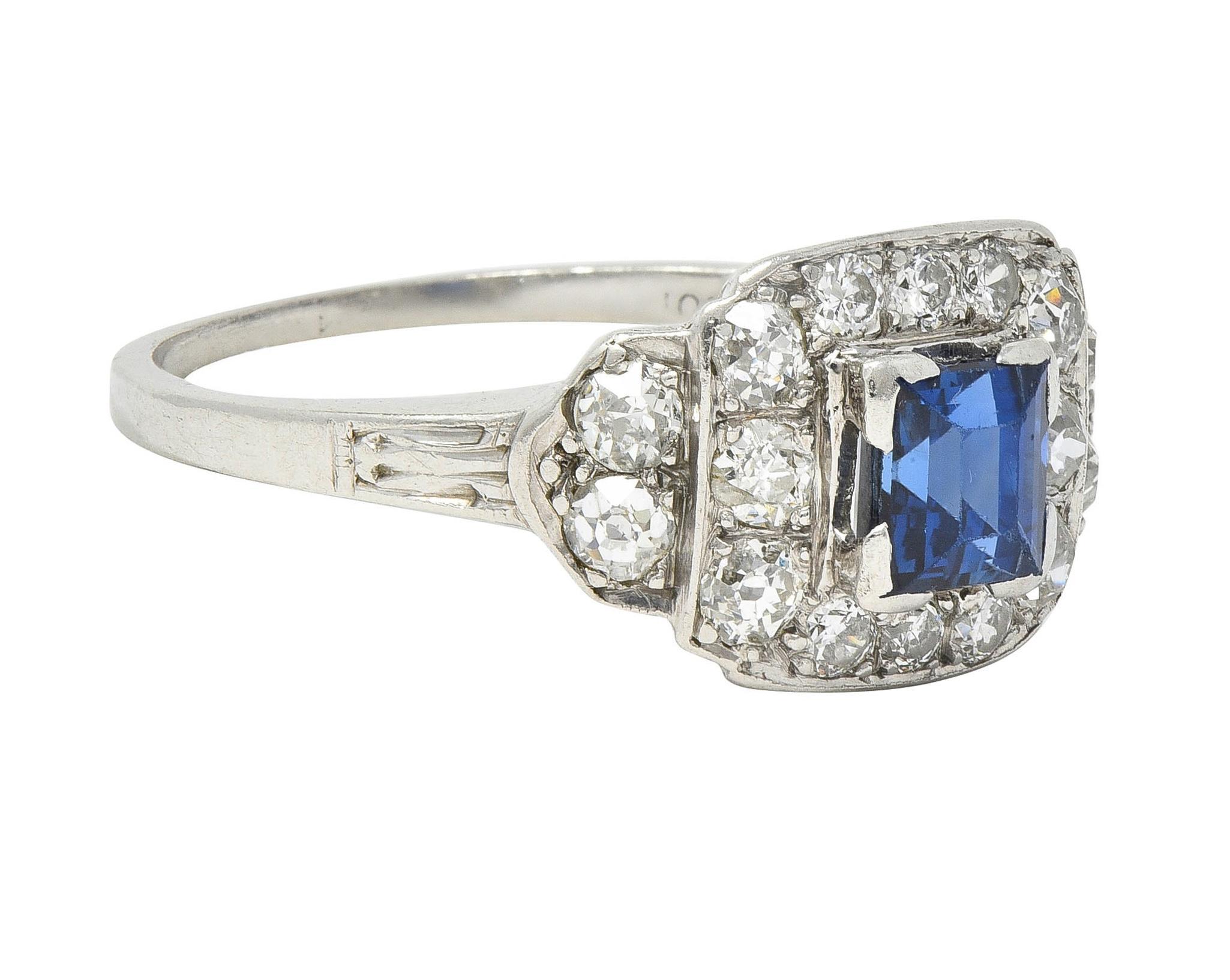 Centering a square step-cut sapphire weighing approximately 0.74 carat 
Transparent medium blue - set in a raised square semi-bezel 
With a clustered surround of old European cut diamonds
Weighing approximately 0.64 carat total 
H color with VS2