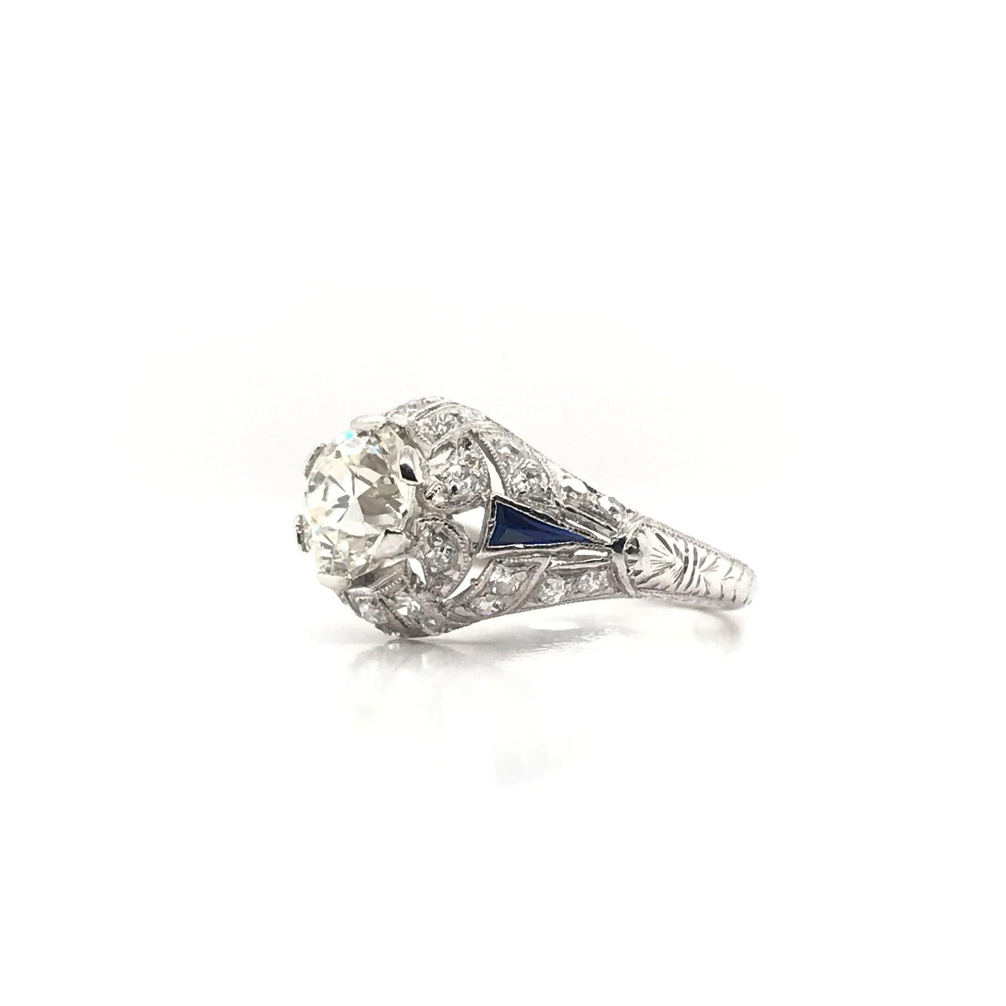 This stunning antique piece was skillfully handcrafted sometime during the Art Deco design period ( 1920-1940 ). The platinum setting features a beautiful 1.39 carat center diamond. The center diamond grades approximately K in color and VS1 in