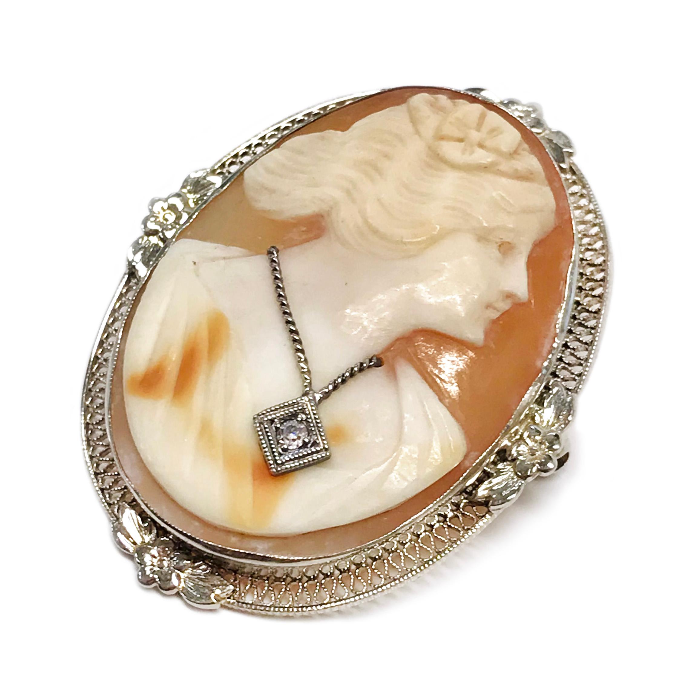 Art Deco 14 Karat White Gold Cameo Diamond Pendant Brooch. The oval cameo is bezel-set. The carved shell cameo is a profile of a woman with a flower in her hair wearing a white gold necklace, the necklace has a single-cut round 1.6mm diamond set in