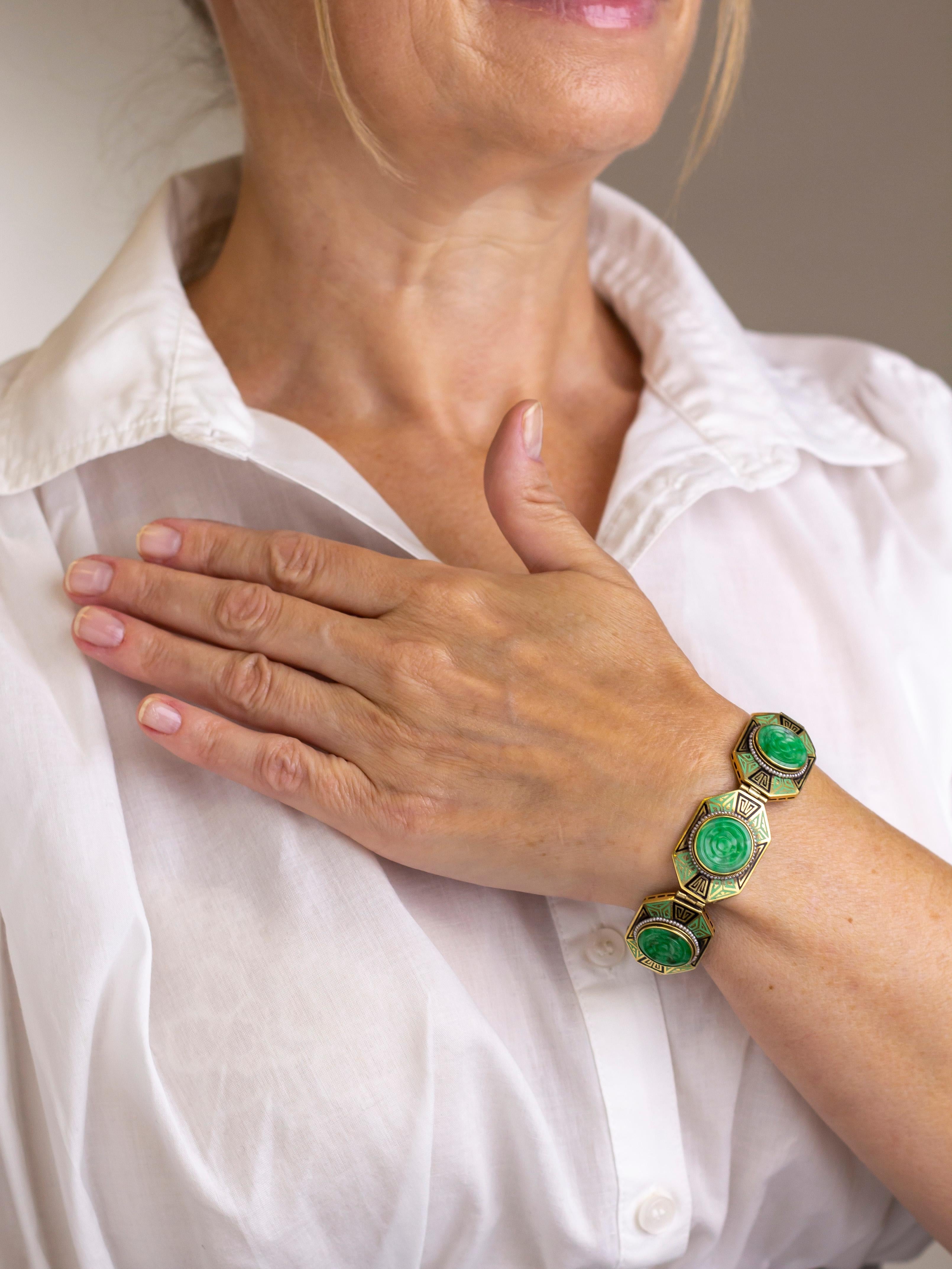 A 14kt yellow gold Art Deco jadeite jade, seed pearl, and enamel bracelet. Each of the 5 links contain a round floral carved disc of a translucent mid green 'A type' jadeite jade, which has been rim set with a twisted wire surround of drilled seed