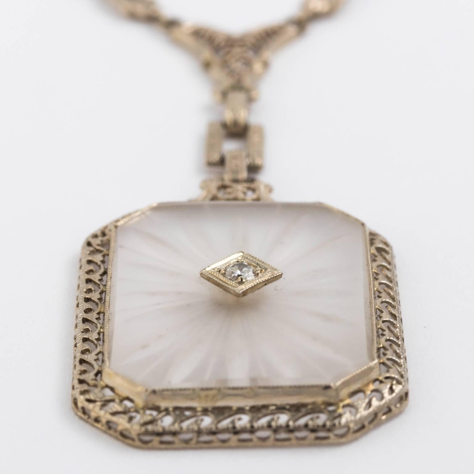 This necklace from 1920's constructed from solid 14K white gold, the center pieces is a hand carved frosted rock crystal with a transition cut diamonds that measures about 5 points. The rock crystal is 1 X 3/4 inches and the pendant dangles about 2