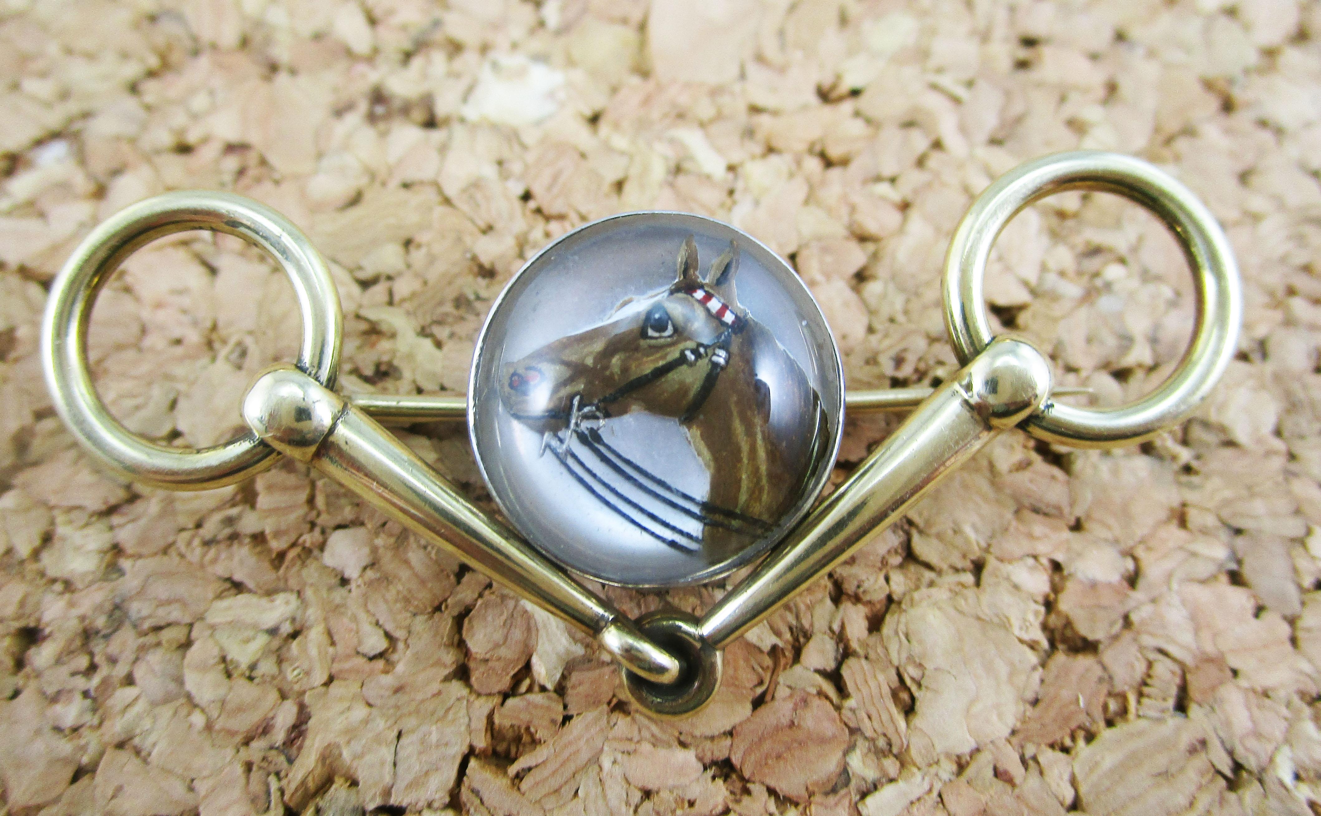 This remarkable Art Deco pin is in 14k yellow gold and features a beautiful hand-painted Essex crystal center in a dramatically angled bridle bit shaped pin. This is the ideal piece of jewelry for the equine enthusiast. Both pin and painting are in