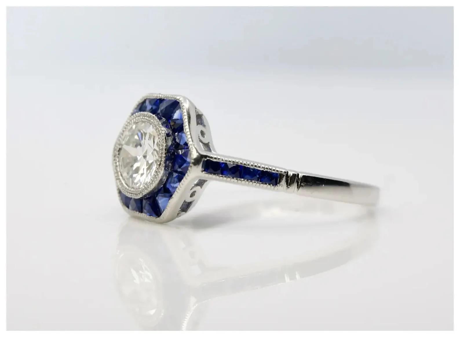 A beautiful Art Deco style diamond and French cut sapphire ring in platinum.

Centered by a bezel set old European cut diamond of 0.75 carats with H color and VS2 clarity.

Framed by 22 French cut blue sapphires of 0.68 cow bordered by miligrain