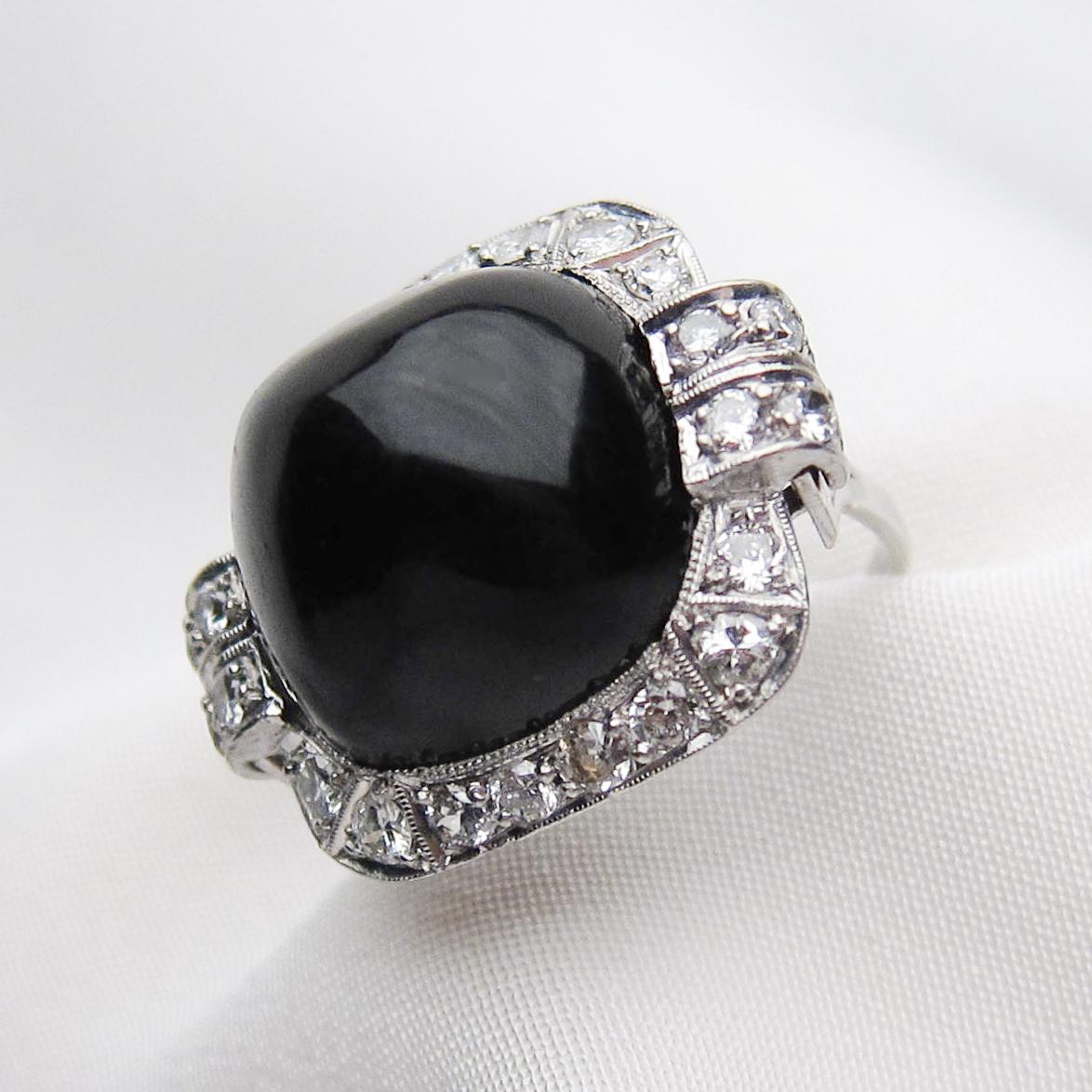 Circa 1930. This fantastic platinum Deco ring features a stunning 14.9 carat sugarloaf natural onyx cabochon surrounded with diamonds. The 24 bead-set, round brilliant-cut diamonds weigh .79 carats with an SI2-I1 clarity and F-G color. The side