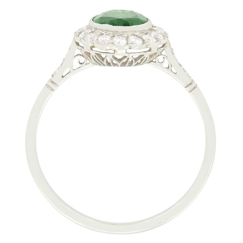 Dating back to the 1920s this stunning cluster ring features a vivid green tourmaline at its centre. The oval cut tourmaline weighs 1.49 carat and is rub over sit within a cluster of old cut diamonds with an additional two adorning each shoulder.