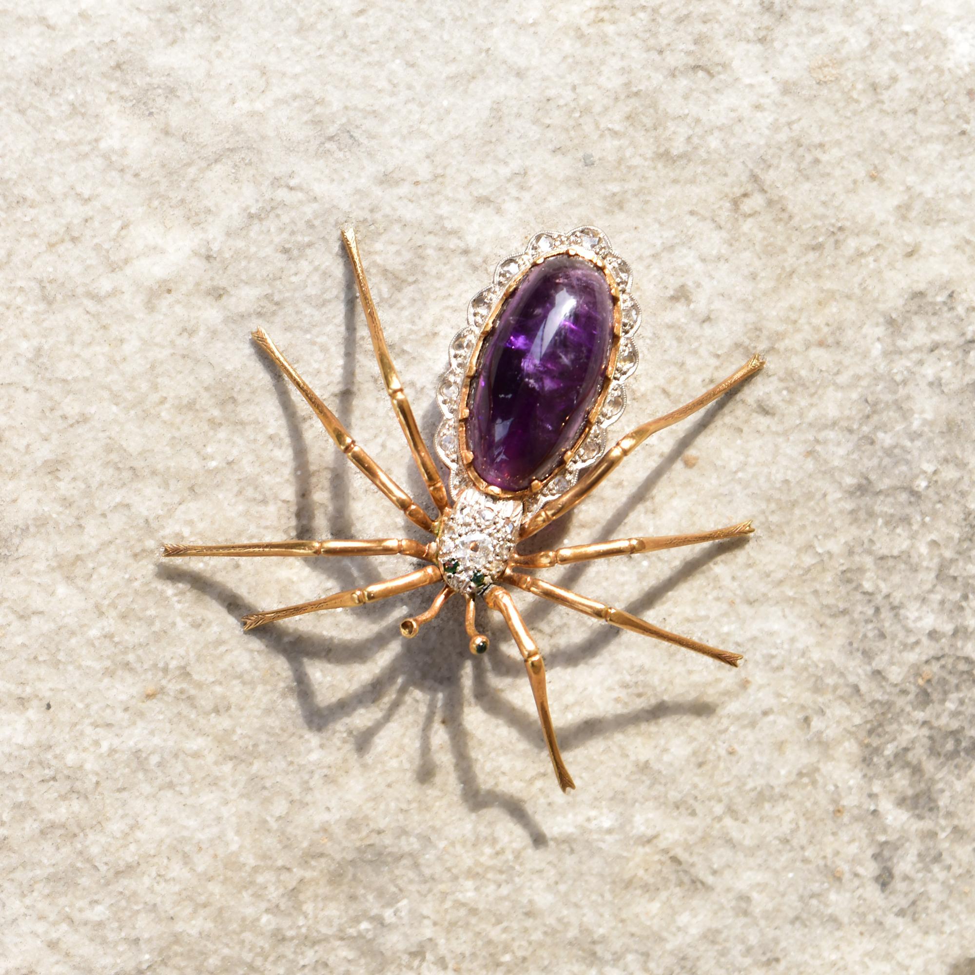 An incredible 14K diamond encrusted amethyst spider brooch with green emerald accents. Features a large yellow gold spider figure with scalloped white gold decoration and large purple amethyst cabochon set in the abdomen. The head of spider is white