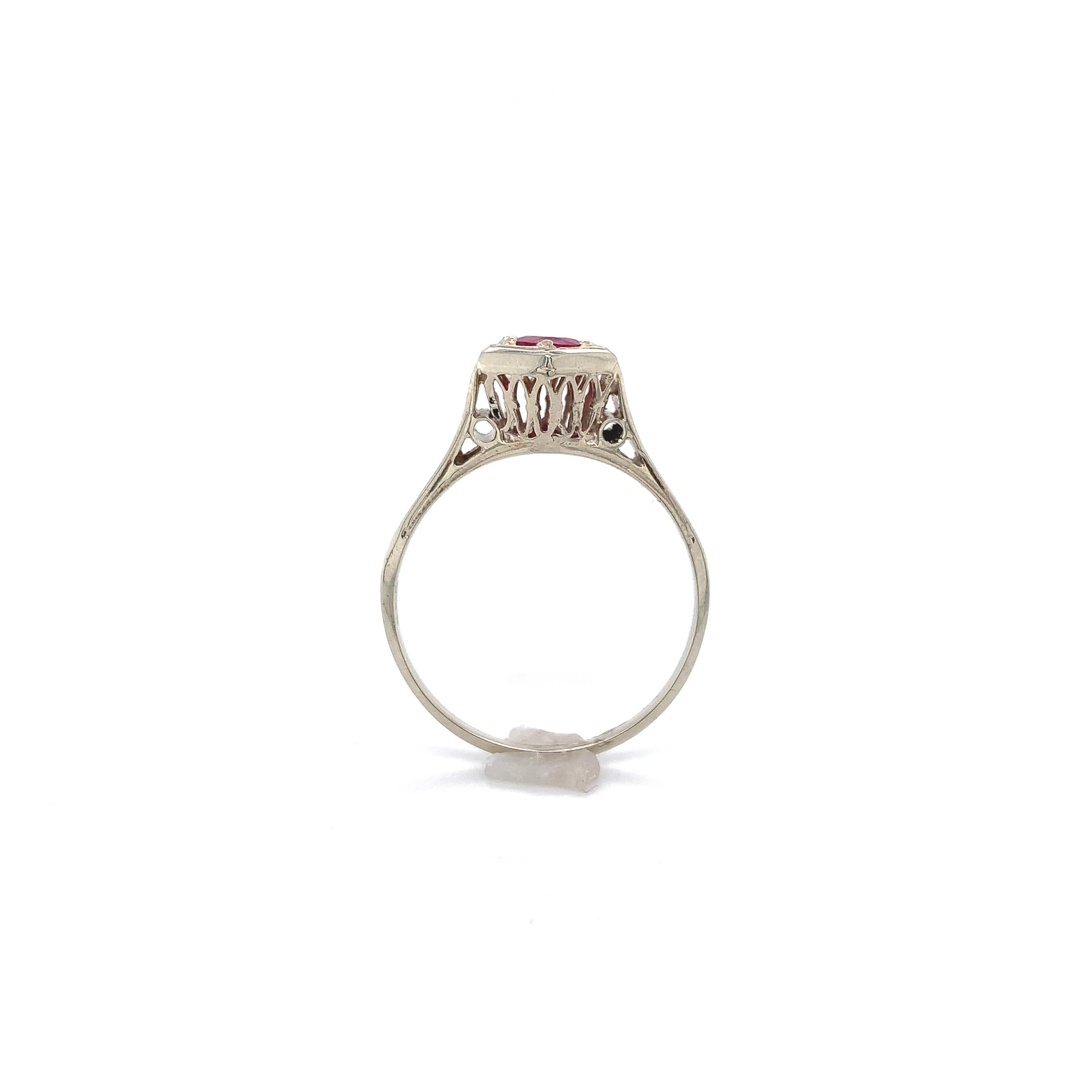 Art Deco 14K white gold filigree ruby ring. The ring features a genuine earth mined round pinkish-red ruby weighing .49cts. The ruby measures about 4.2mm and has all new bead prongs. There is hand engraving on the sides. The ring fits a size 7