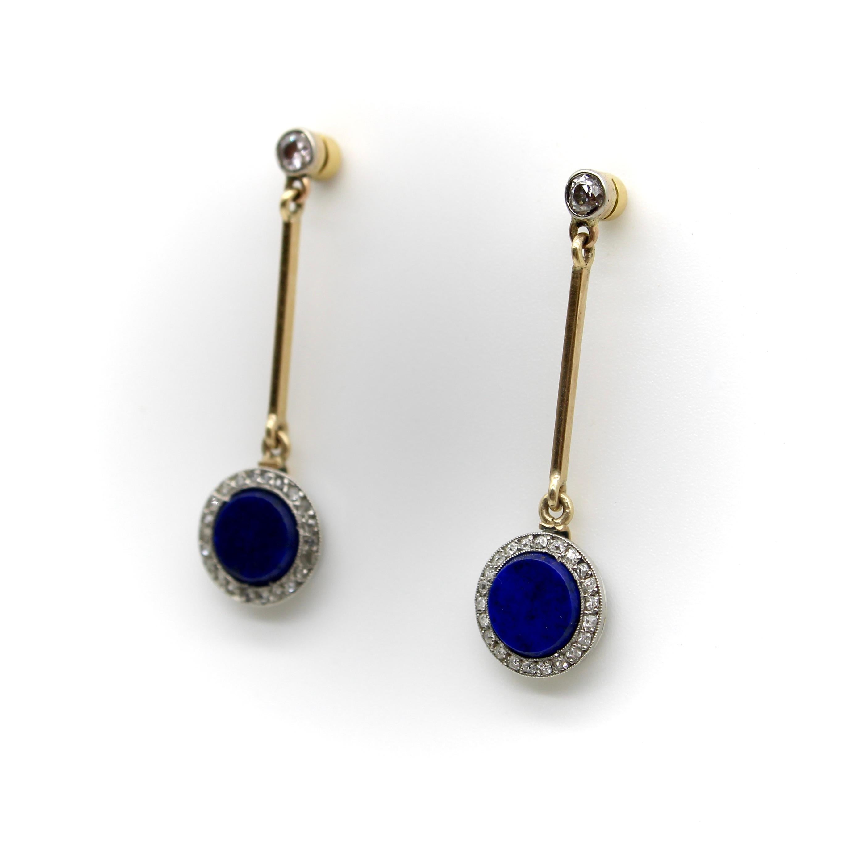 Datant de l'époque Art déco, ces boucles d'oreilles en or 14k présentent une tablette circulaire de lapis-lazuli entourée d'un halo de diamants, suspendue à un diamant de taille européenne ancienne. Le diamant situé au sommet de la boucle d'oreille