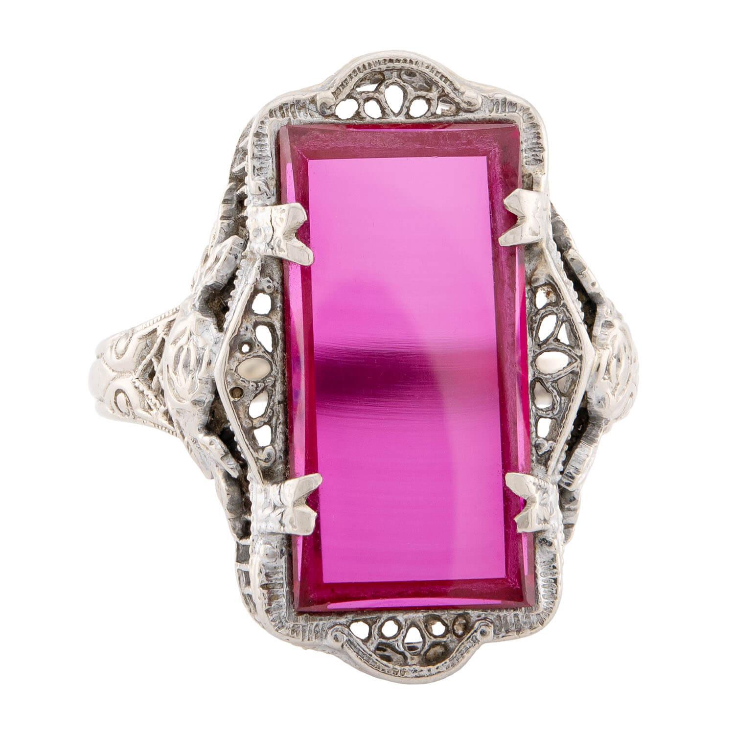 A simply beautiful ring from the Art Deco (ca1920s) era! Crafted in 14k white gold, this fabulous piece features a colorful design! The centerpiece features a rectangular-shaped piece of pinkish-red glass, which is held within a four-prong setting.