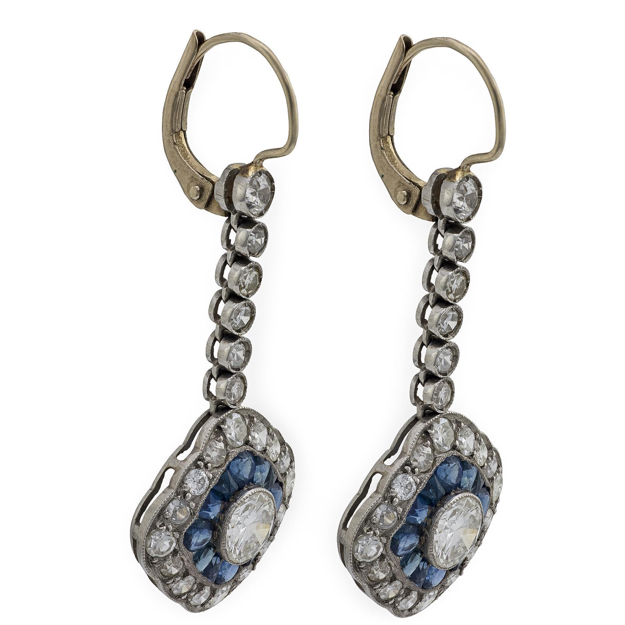 A beautiful pair of earrings from the Art Deco (ca1920s) era! Crafted in 14k white gold and platinum, each earring begins with a circular surmount, which features a bezel-set single cut diamond. The top diamond is followed by 5 similar, yet smaller