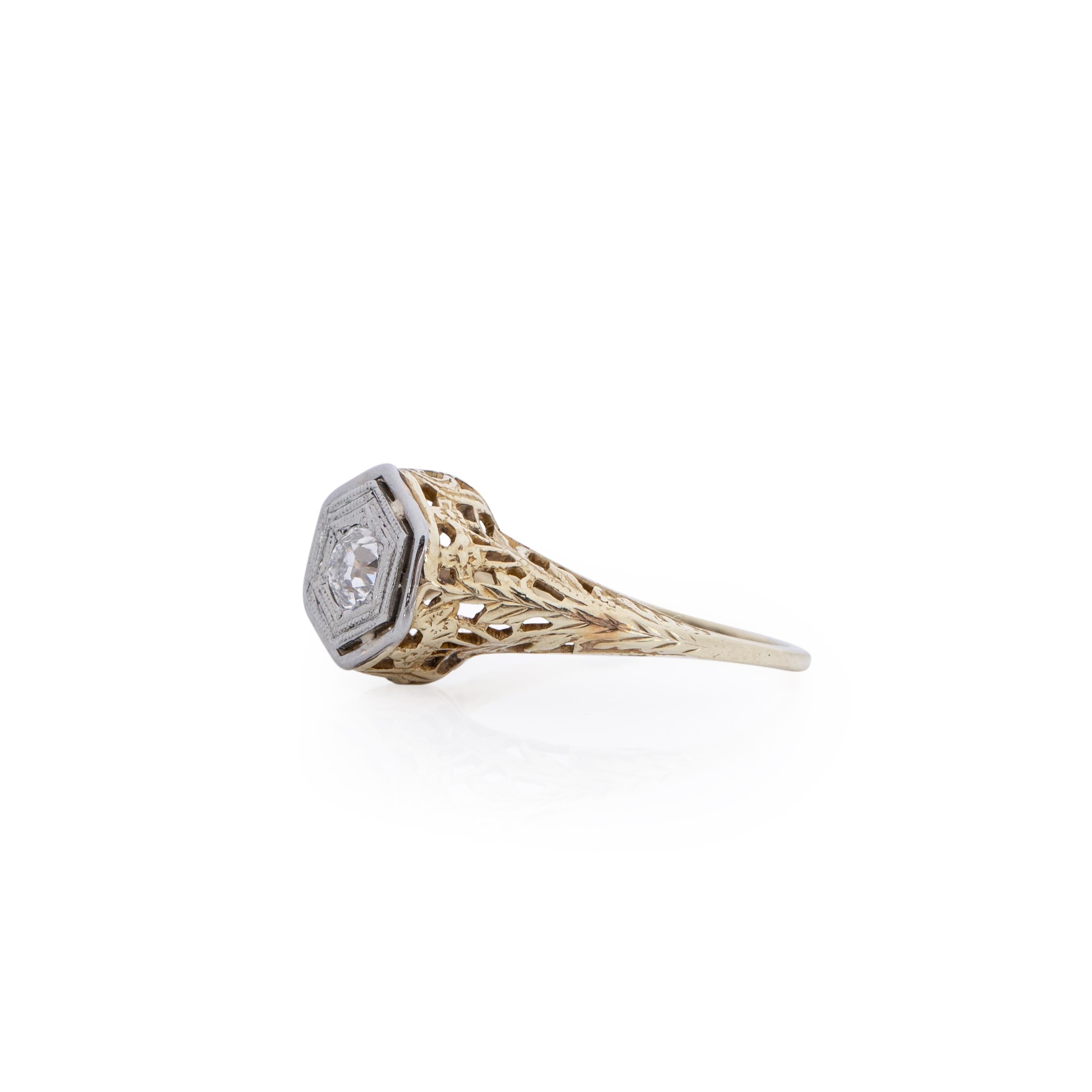 Here is a art deco solitaire filigree ring. A dainty and elegant classic. This ring is crafted in 14K yellow and white gold giving this piece a beautiful two tone affect. Along the yellow gold shanks is a intricate flora design of leaves, that wrap