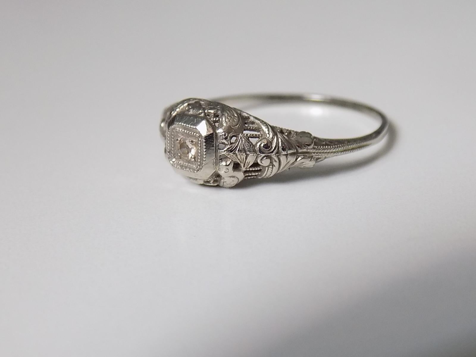 A Classic Art Deco 14 carat white Gold and Diamond solitaire ring in fancy setting. American origin.
Size O UK, 7.5 US.
Height of the face 7mm.
Weight 1.4gr.
Marked 14 for 14 Carat Gold