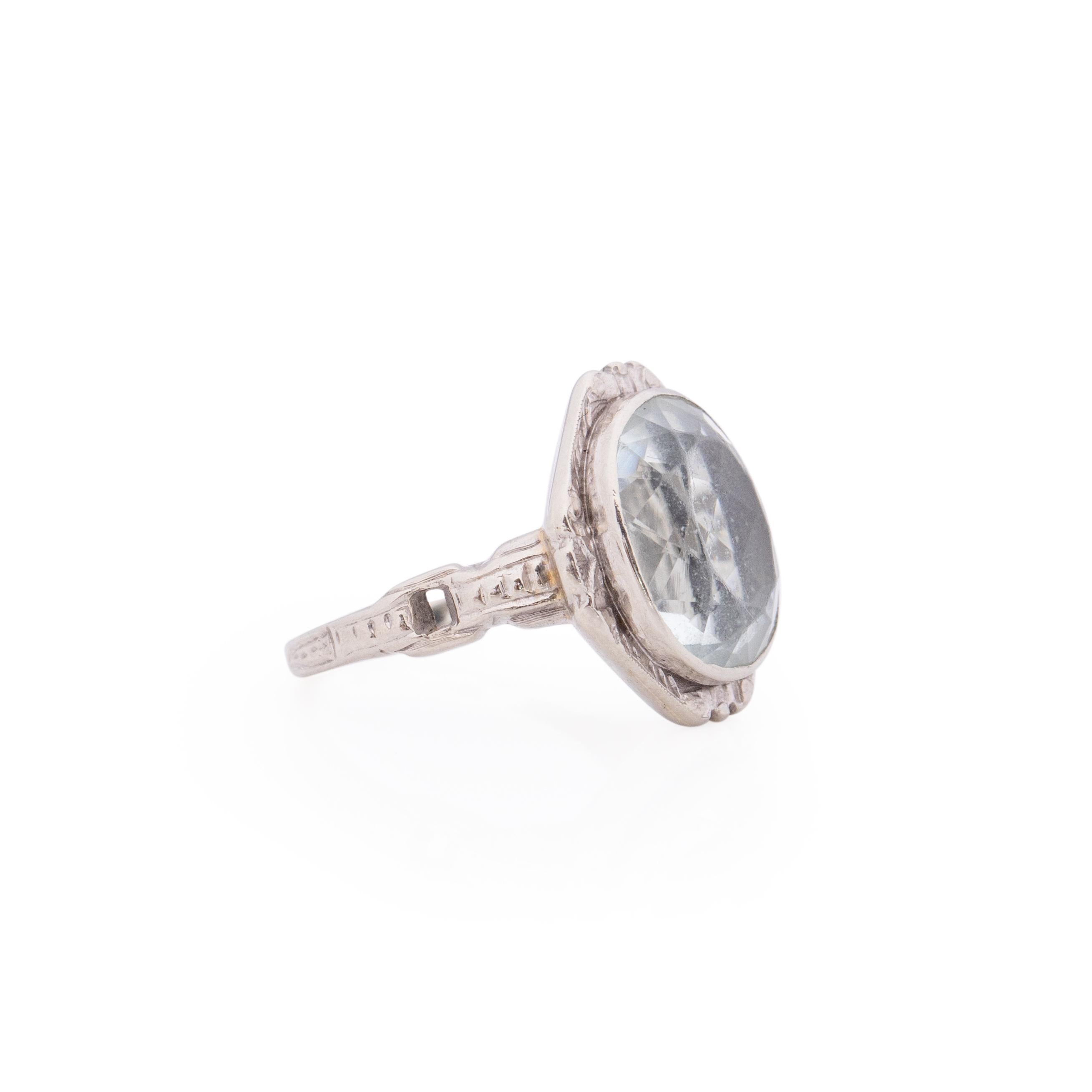 Here we have a breath taking pale blue antique oval aquamarine fashion ring. This gem is being held in by a 14K white gold bezel that has a simple carved halo, adding to the classic art deco look. Down the shank is a elegant buckle design,
