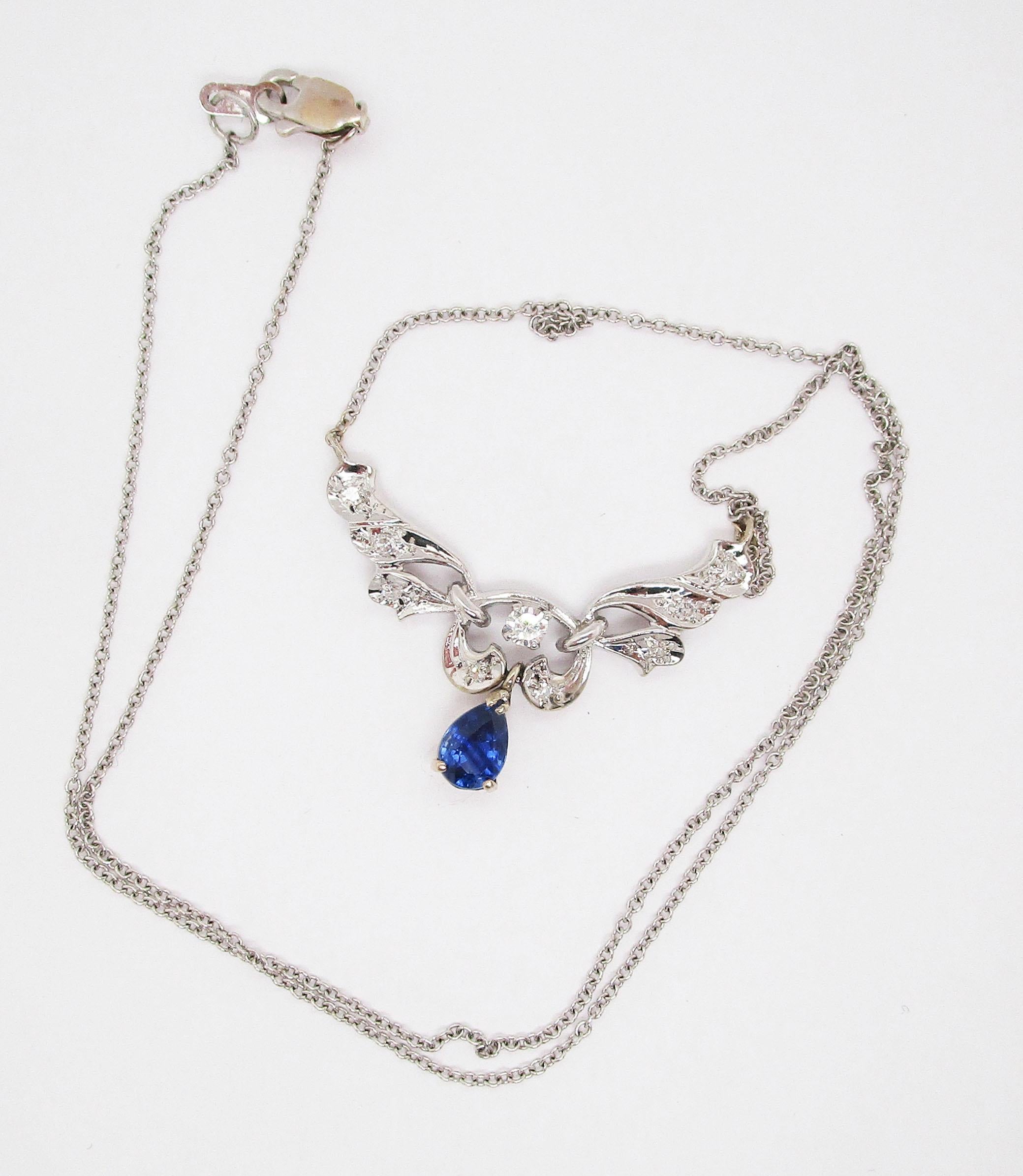This necklace boasts a definitive design in 14k white gold and enhanced by diamonds and a stunning pear-shaped blue sapphire. The long layout of the necklace makes for a dramatic look on the neck. The brilliant white of the diamonds set against