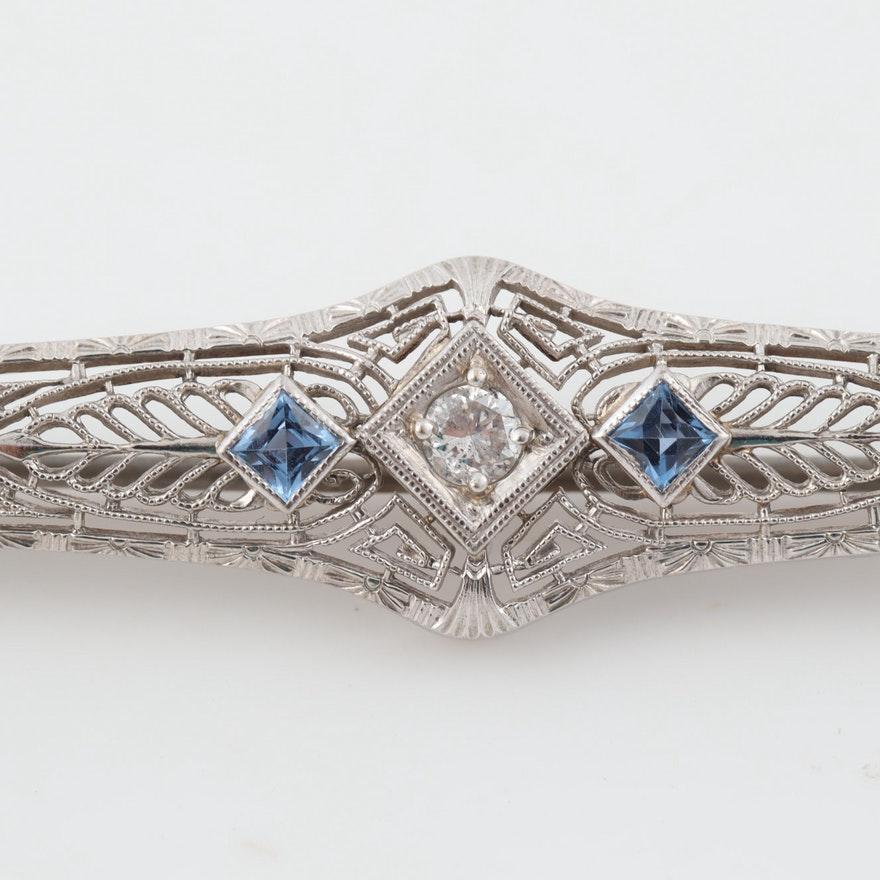 Description: 
This lovely Art Deco Brooch crafted in 14 karat white gold features intricate filigree designs highlighted with three bright old cut diamond and two french cut blue sapphires.

This is a true antique piece, and we are honored to offer