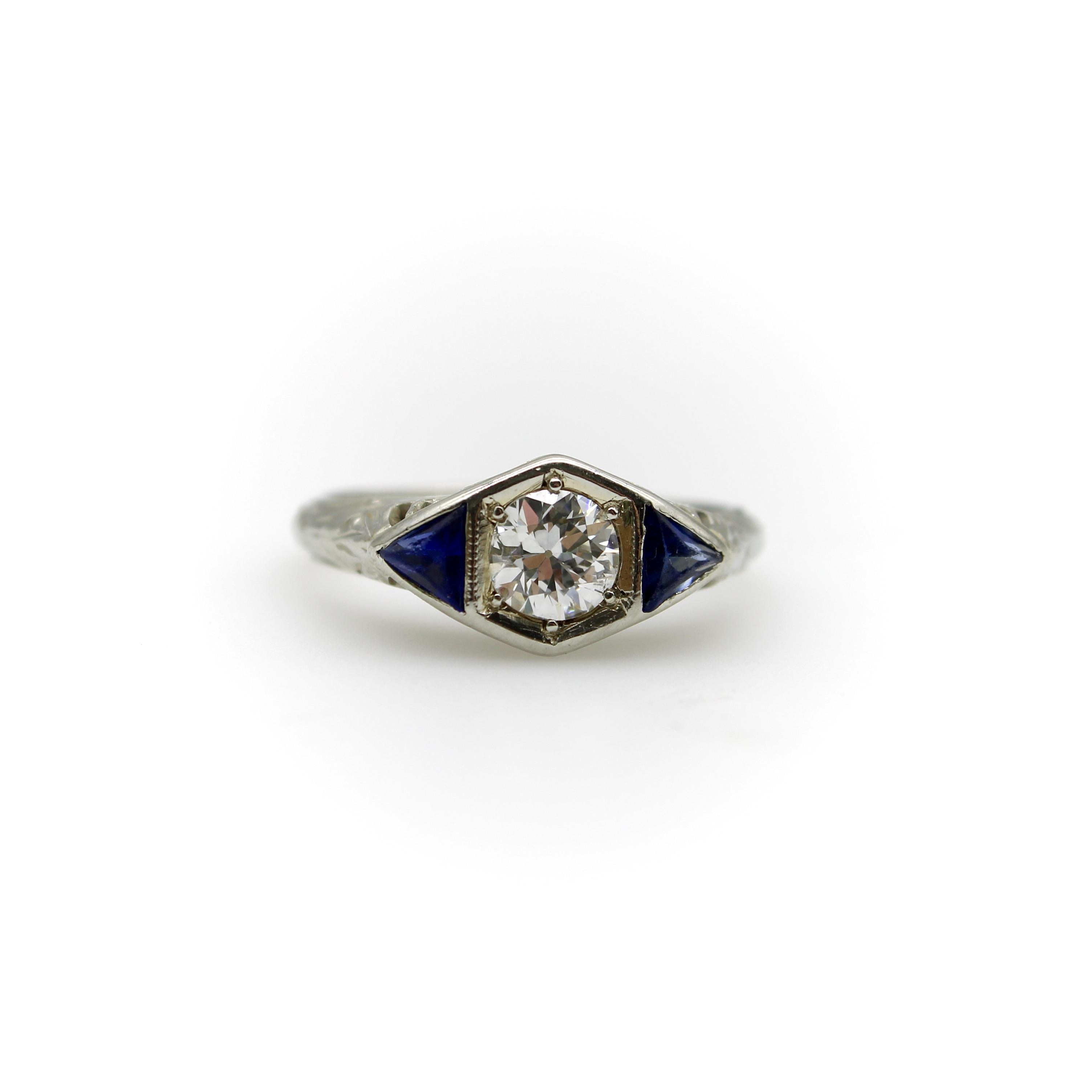 Magnifique pièce d'époque de l'Art déco, cette bague en or blanc 14 carats présente tous les éléments classiques qui font la particularité de l'époque de l'Art déco. Le diamant central est maintenu dans une monture géométrique horizontale allongée,