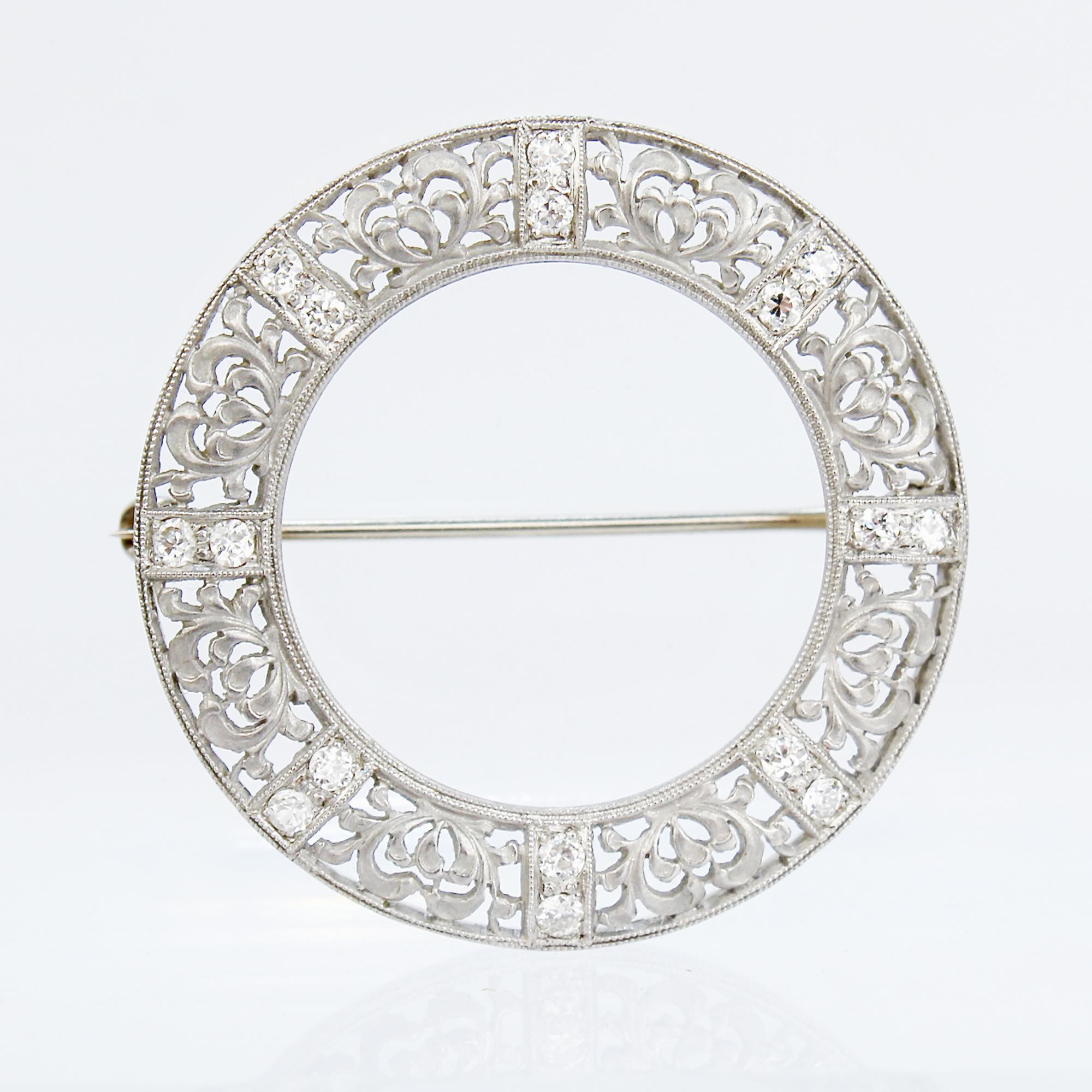 A fine Art Deco white gold & diamond round filigree brooch or pin.

In 14k white gold.

The gold is filigreed into rocaille devices and set with 16 round cut diamonds set in pairs in the cardinal and ordinal directions.

With a pin and safety clasp