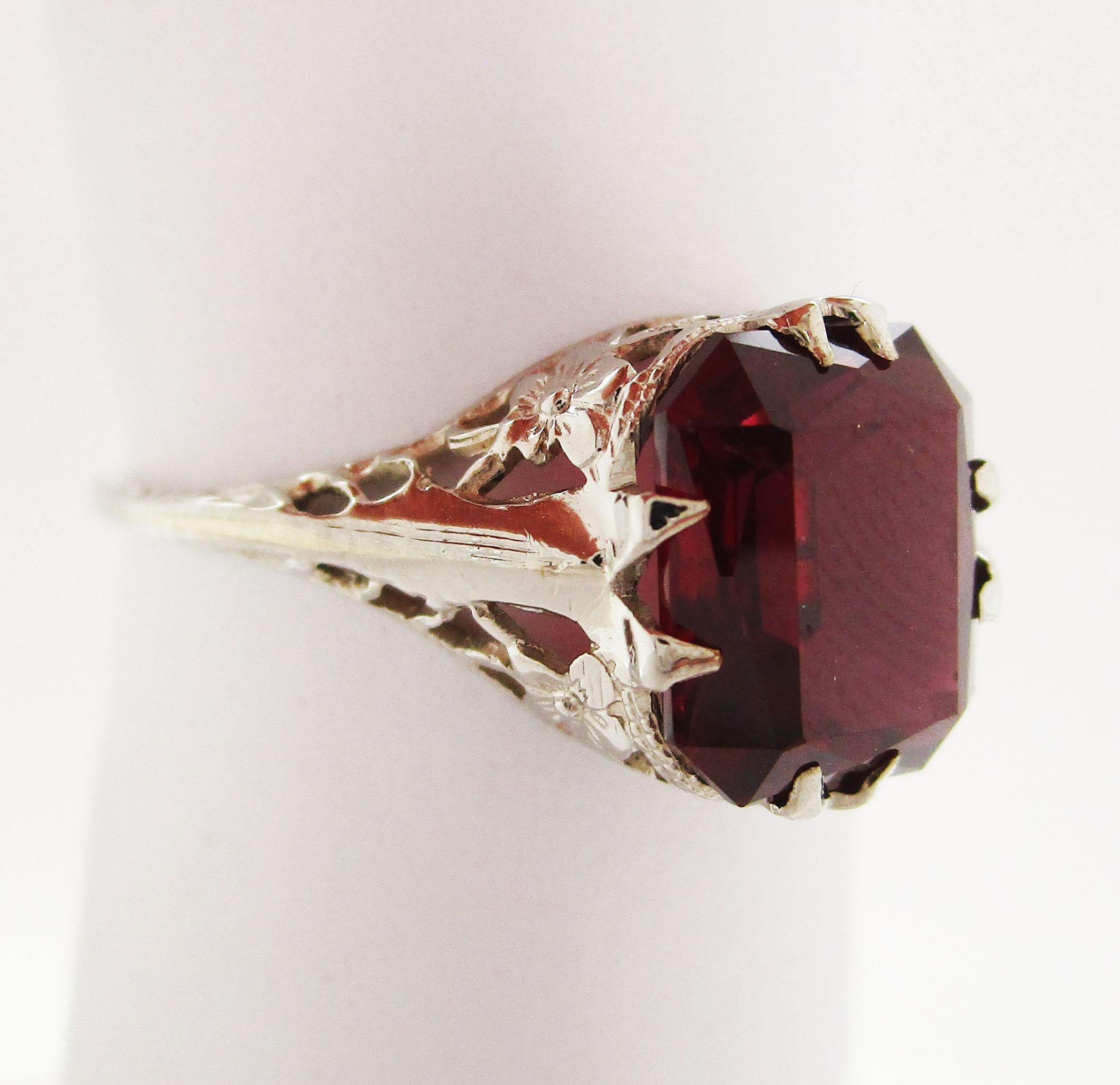 This is an absolutely stunning Art Deco ring in 14k white gold with romantic filigree detailing and a gorgeous red garnet center. This is a classic Art Deco ring with a subtle elegance! The shoulders of the ring have engraved details, while the
