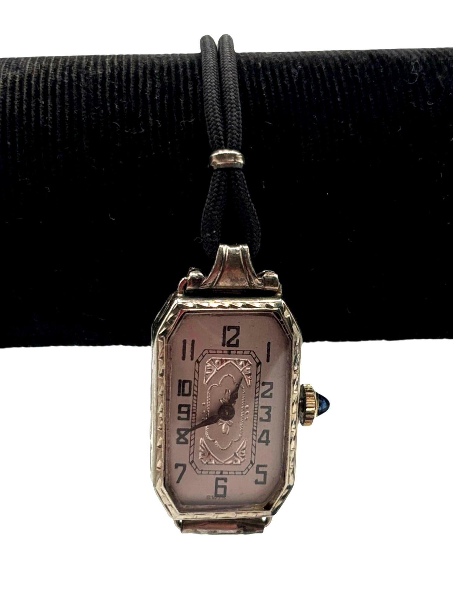 Original 1925 W.C Company Swiss-made Art Deco ladies' watch is a striking piece, featuring a 14K white gold-filled case adorned with intricate geometric engravings and blue Sapphire. The rectangular dial is framed by a stepped design, showcasing