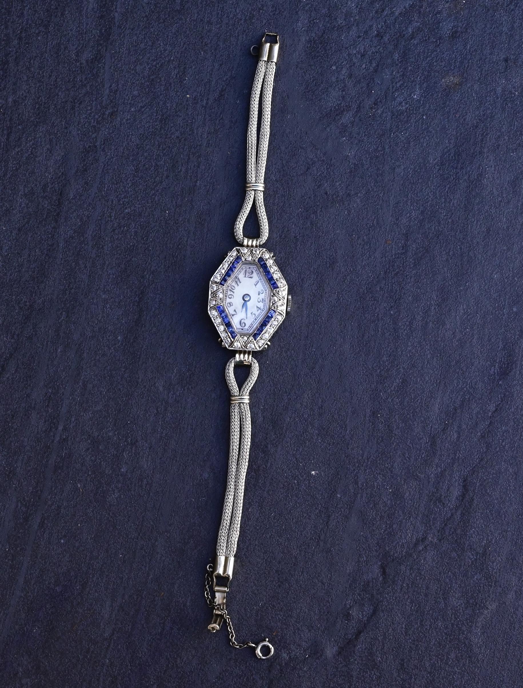 Titel:
Art Deco 14K Weißgold & Platin Damenuhr mit Diamanten und blauen Saphiren

Beschreibung:
Diese exquisite Damenarmbanduhr aus der Art-Déco-Ära ist aus 14 Karat Weißgold und Platin gefertigt und zeigt die ikonische geometrische Eleganz und die