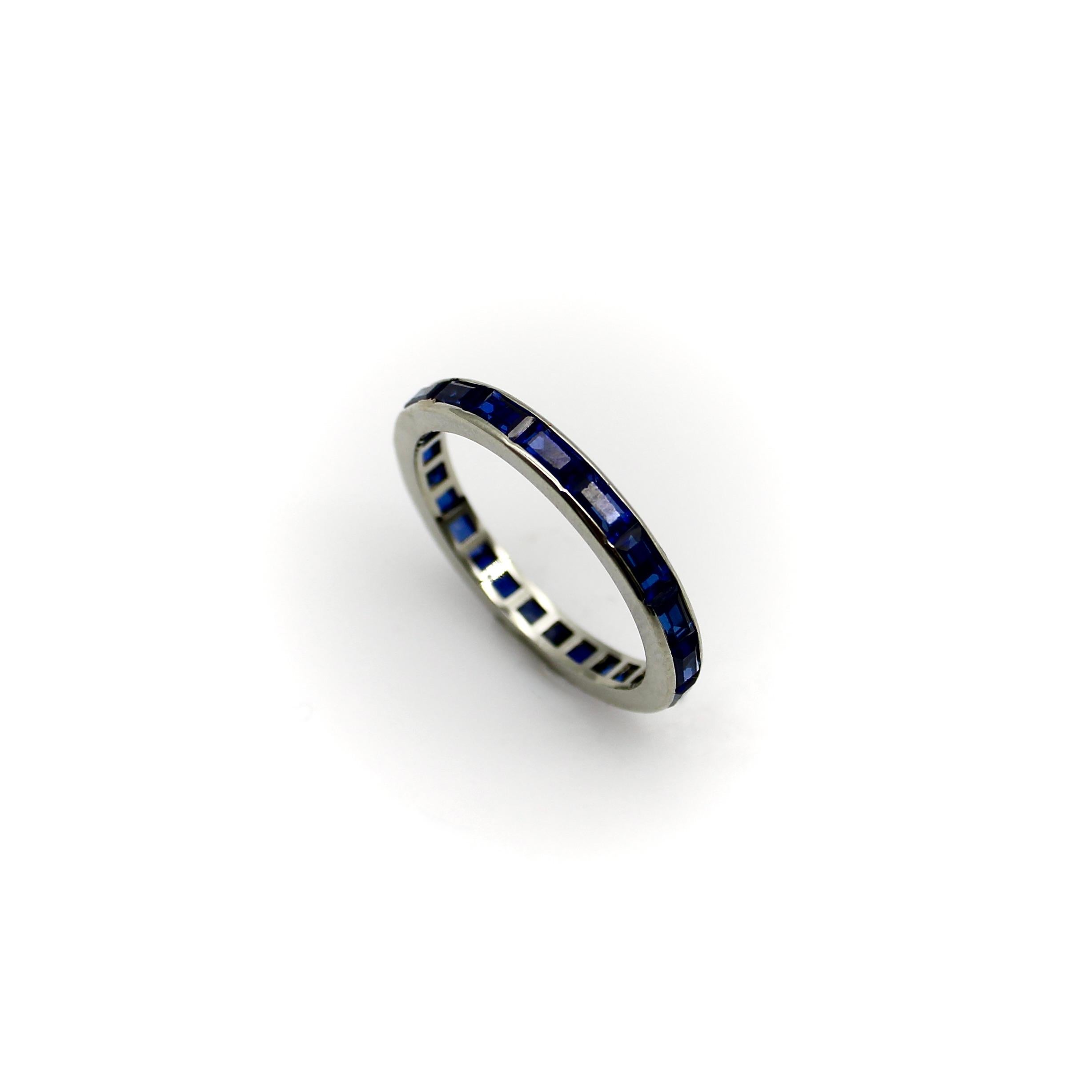 Ein 14k Gold Art Deco Ewigkeit Band mit Kaliber geschliffenen Saphir Baguettes, die sich um den Ring. Die kanalgefassten Saphire haben ein ziegelsteinähnliches Aussehen und sind langgestreckt, was ihnen ein klassisches, elegantes Aussehen verleiht.