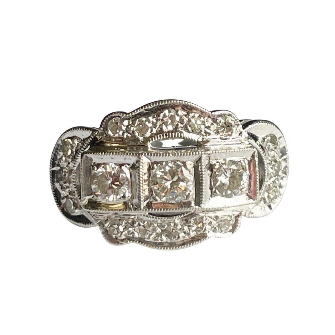Hier haben wir einen eleganten dreireihigen Ring aus 14 Karat Weißgold mit drei Steinen. Die geraden Schäfte gehen in ein fließendes Design mit Wellenschliff über, das dem Zentrum mit drei Steinen ein haloartiges Aussehen verleiht. Dieser mit