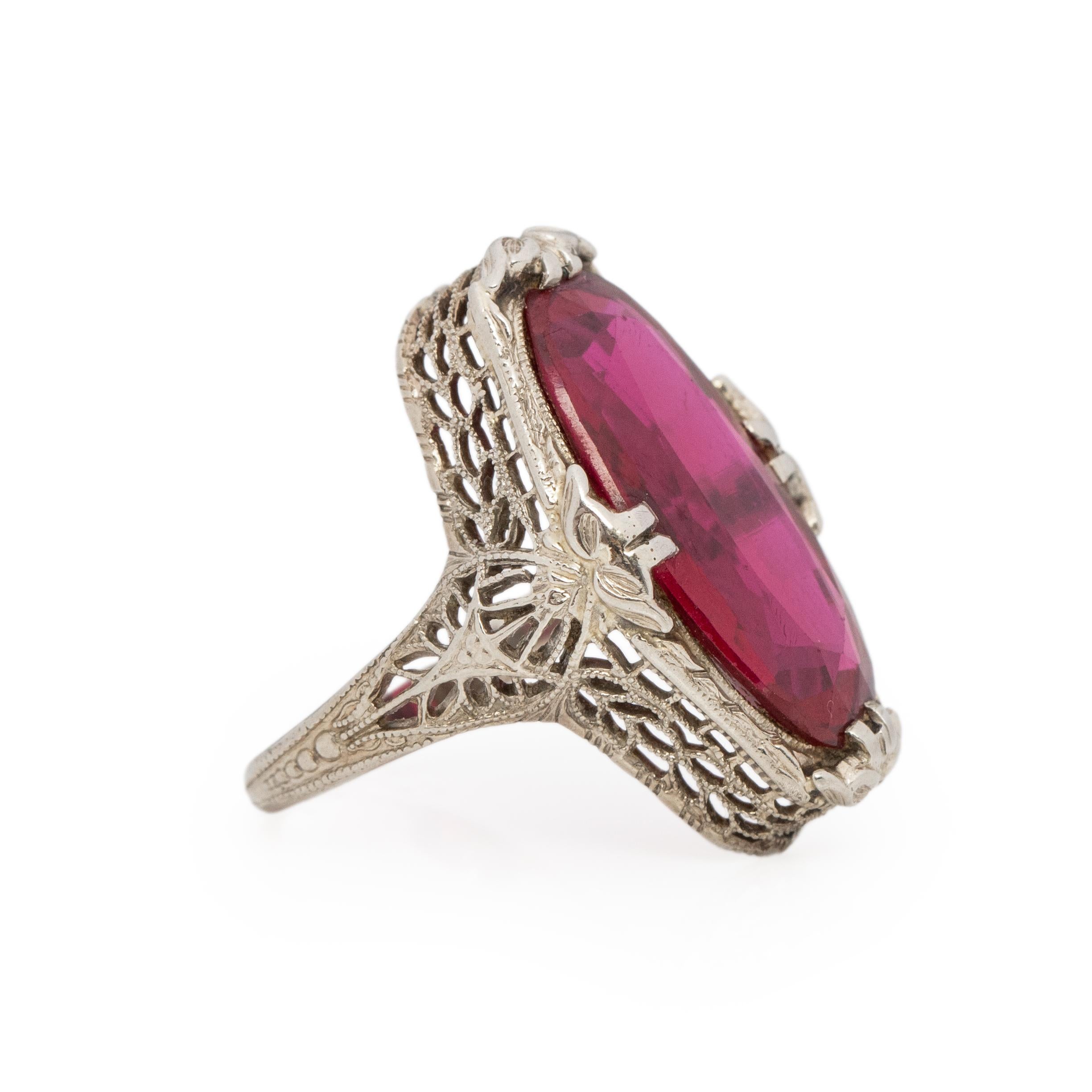 This art deco beauty, has breathtaking filigree work crafted in 14K white gold the flowing floral and geometric patterns holds a vibrant oval brilliant cut glass gem. This glass gem has a beautiful vibrant red hue. The unique long oval shapes, sits