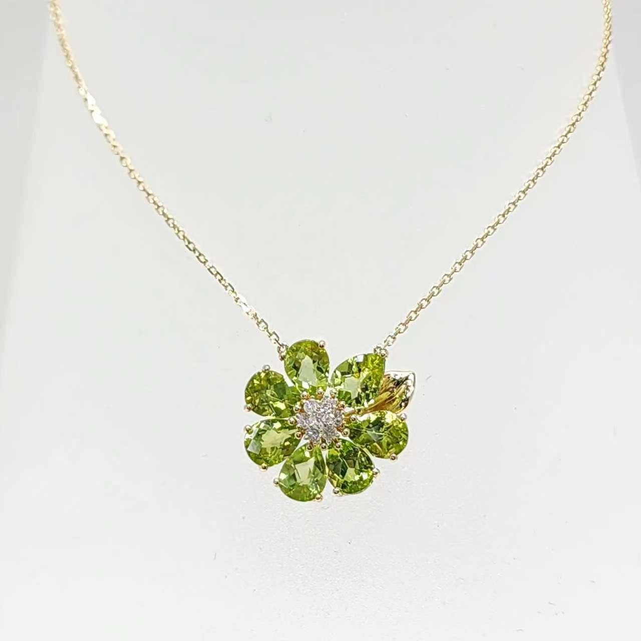 Scopri il fascino incantevole della nostra collana di peridoto in oro giallo 14K, un capolavoro fiorito con sette vibranti gemme di peridoto per un totale di 5,39 carati. Questo pendente a forma di fiore cattura l'essenza della natura con petali di