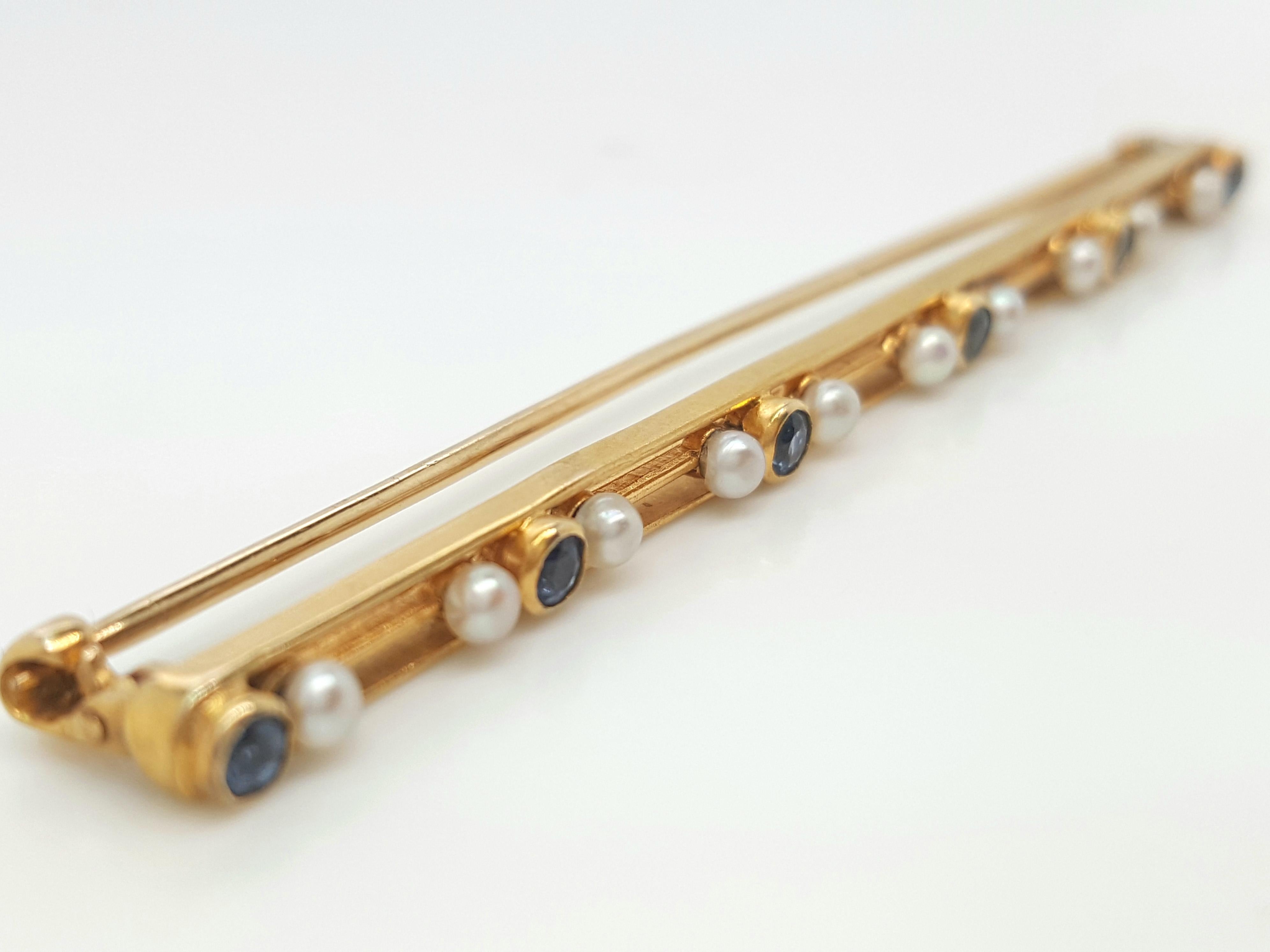 Art Deco 14 Karat Yellow Gold Sapphire and Seed Pearl Bar Brooch. This chic brooch features six round blue sapphires bezel set in between seed pearls that are the perfect feminine accent, all are set in 14 karat yellow gold,  completed by a pinstem