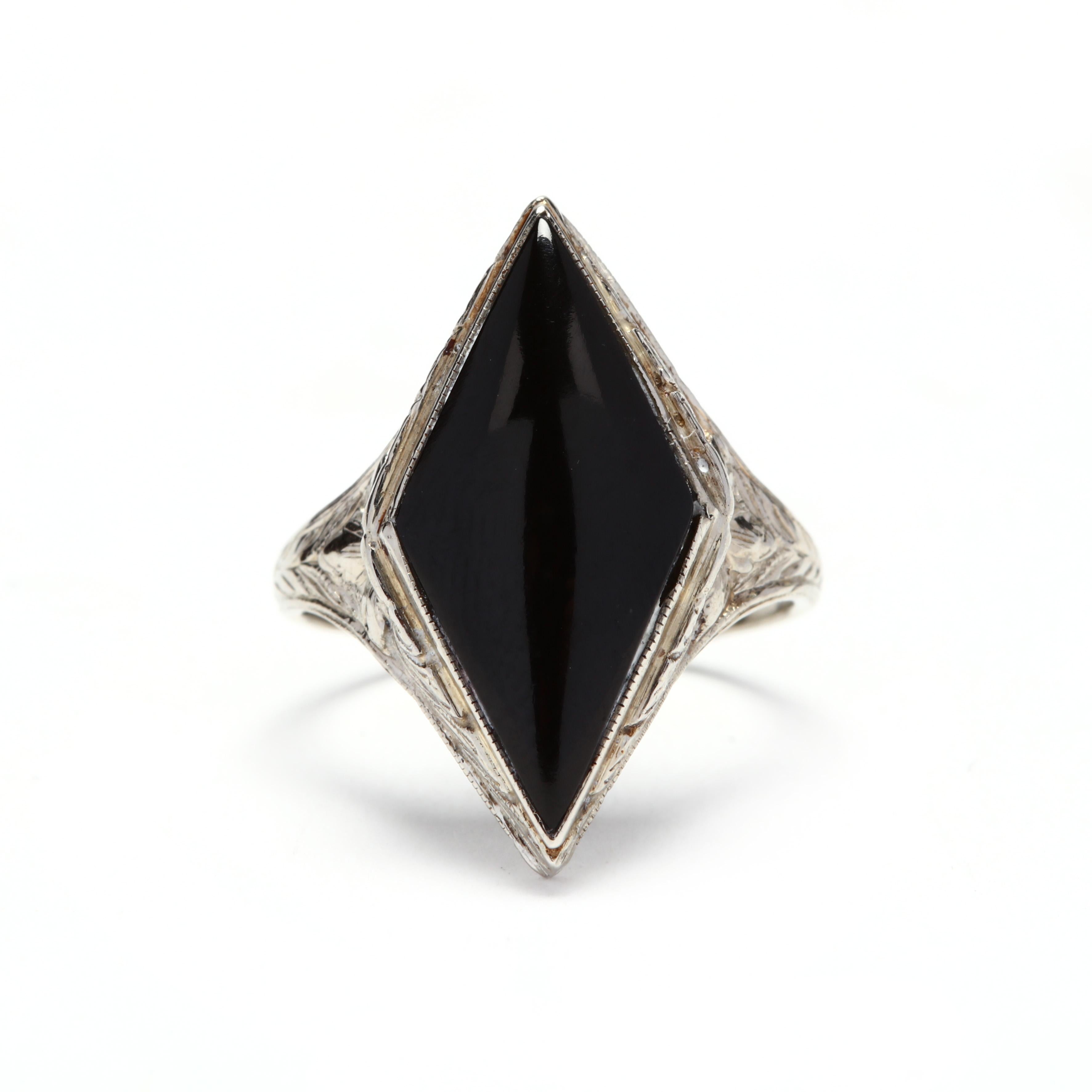 An Art Deco 14 karat white gold black onyx ring. In a navette shape, a bezel set cabochon marquise black onyx stone, set in an ornately engraved mounting.

Stones:
- black onyx, 1 stone
- cabochon marquise cut
- 20 x 10 mm

Ring Size 5.25

Width