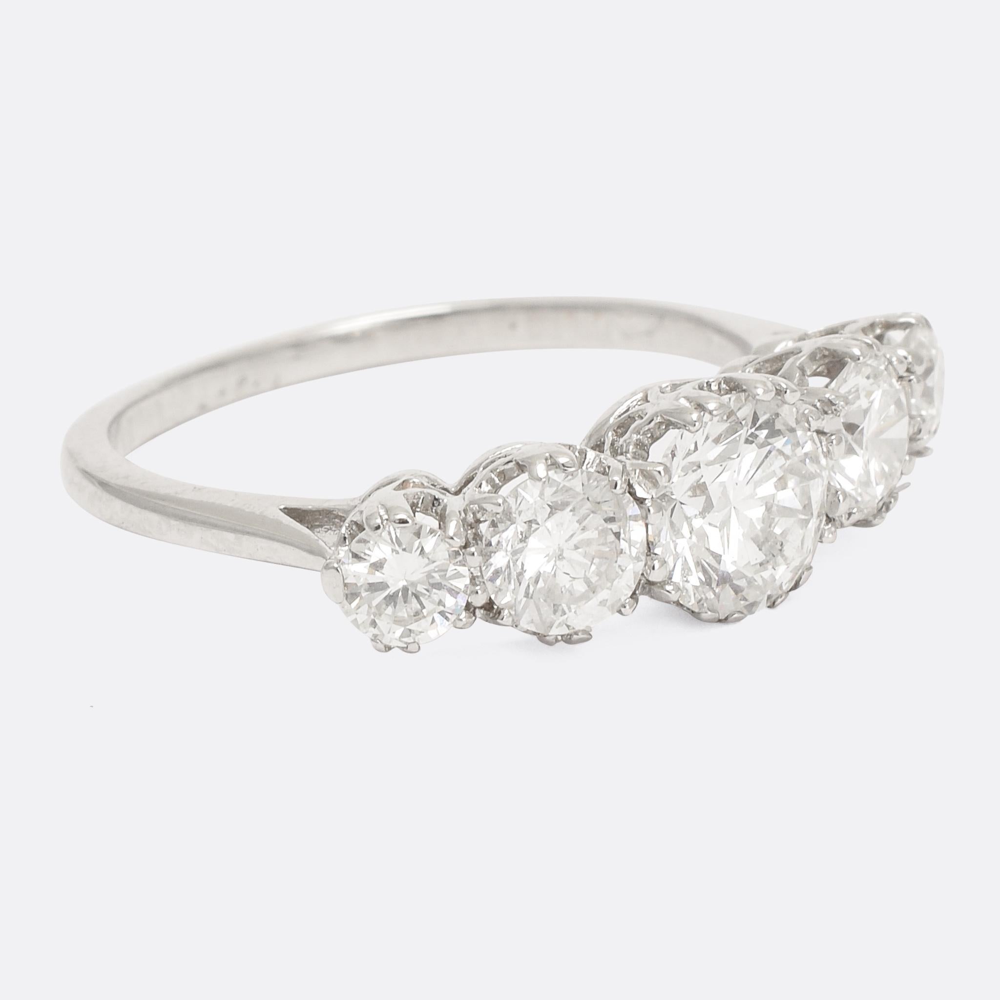 A particularly well proportioned 5-stone diamond ring dating from the Art Deco period, circa 1920. The stones rest in claw mounts, with an elaborate openworked gallery and subtly pinched shoulders. It's modelled in 18k gold and platinum, home to 1.5