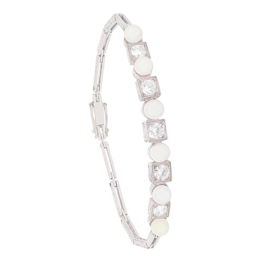 This art deco bracelet features a row of alternating pearls and transitional cut diamonds. The five diamonds total to 1.50 carat, and are G colour and VS2 clarity. They diamonds are set in square shaped settings, contrasting to the roundness of the