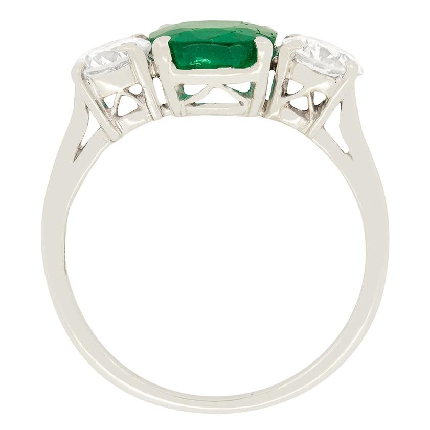 A magnificent 1.50 carat natural emerald with a Columbian origin, sits between two sparkling transitional cut diamonds. The diamonds have a combined weight of 1.00 carat and have been estimated as F in colour and VS-SI in clarity. All three stones