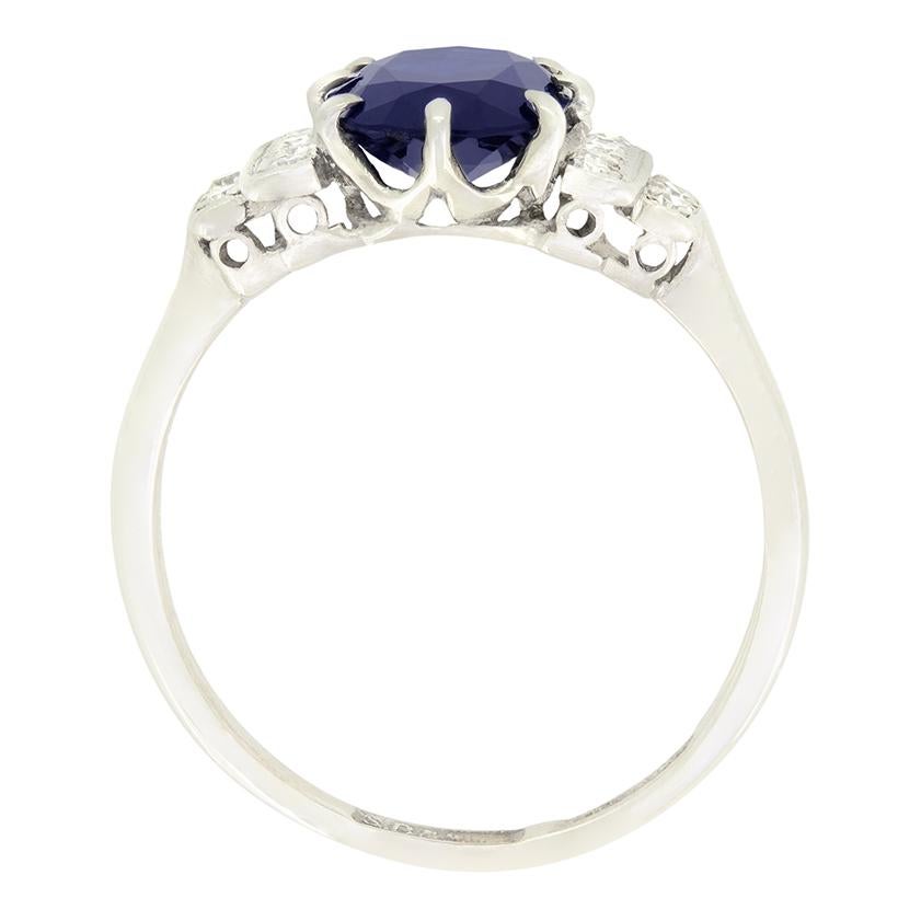 Ein atemberaubender tiefblauer Saphir steht im Mittelpunkt dieses klassischen Art-Déco-Rings. Der Saphir ist ein oval geschliffener Stein mit einem Gewicht von 1,50 Karat. Zwölf funkelnde Diamanten im Acht-Schliff flankieren den Saphir auf den