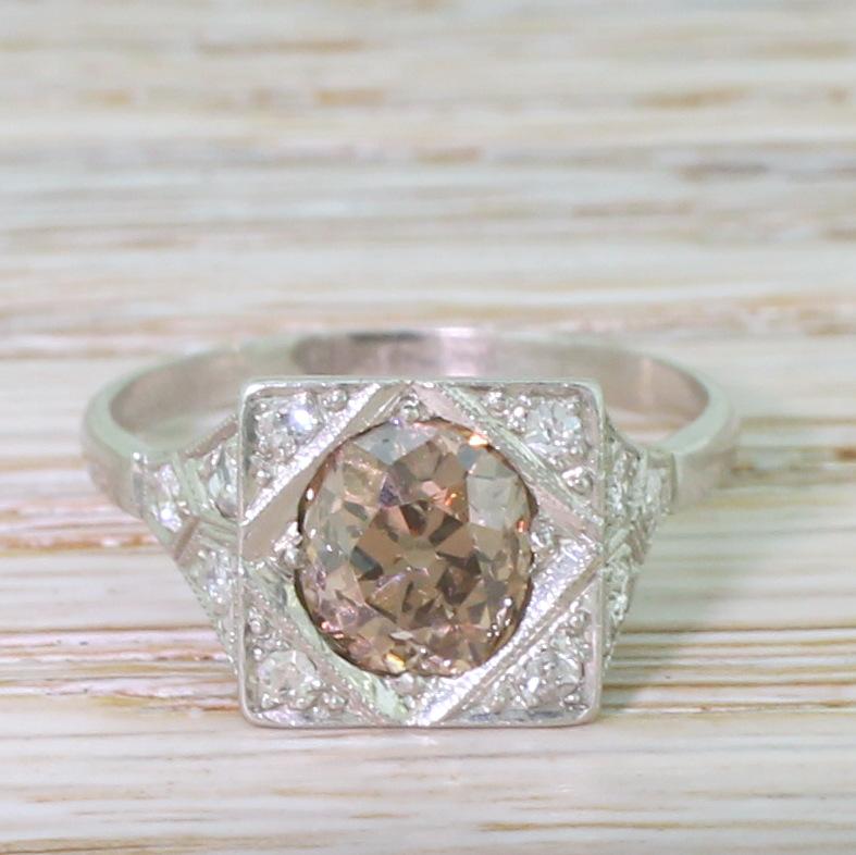 An incredibly beautiful – and undeniably unique – Art Deco diamond engagement ring. The centre old cut diamond is a distinctive and glowing orangey brown, the richness of the colour highlighted by the four white smaller old cuts set in the corners