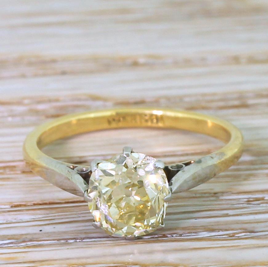 An immensely beautiful old cut diamond takes centre stage in this antique engagement ring. The cushion shaped old mine cut is internally clean, impressively lively and displays a distinct, warm champagne hue. The stone is secured in an eight-claw