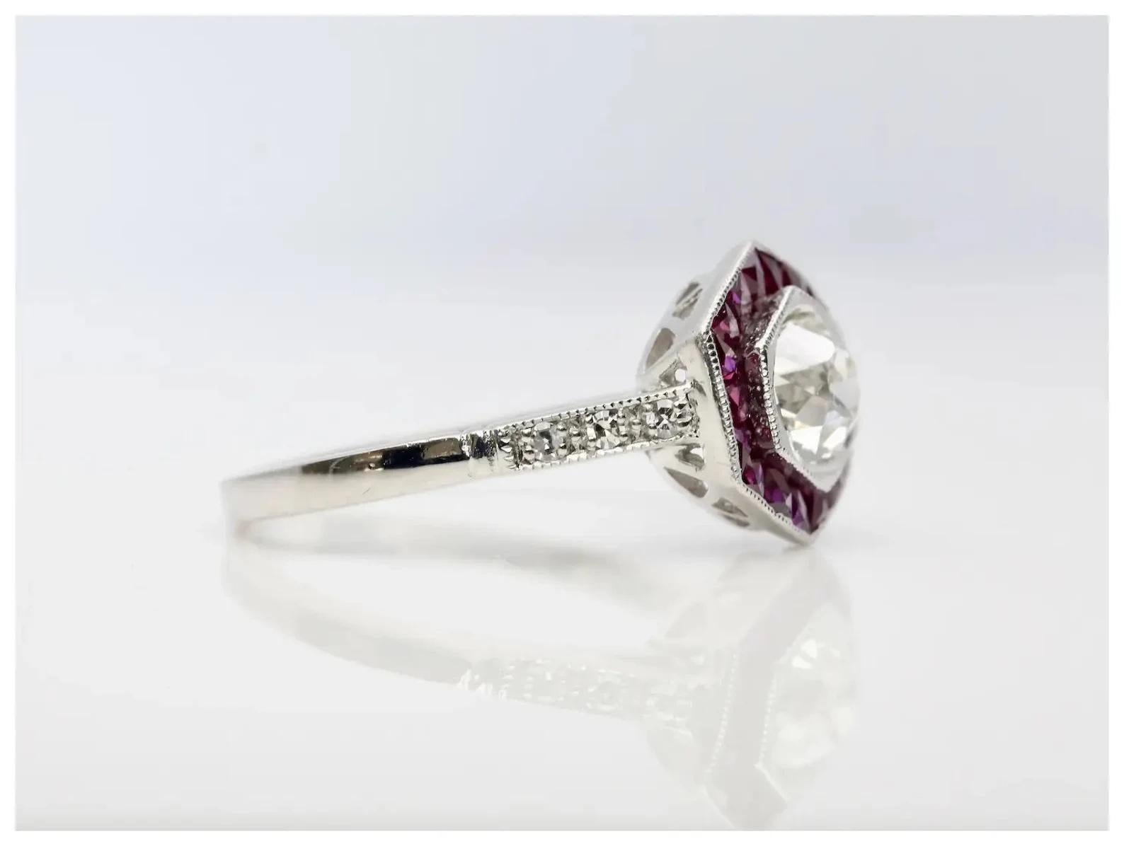 An Art Deco style diamond, and French cut ruby engagement ring in platinum.

Centered by a 0.75 carat old European cut diamond of J color and VS2 clarity set in a miligrained platinum bezel.

Framed by 0.72ctw of channel set French cut rubies and