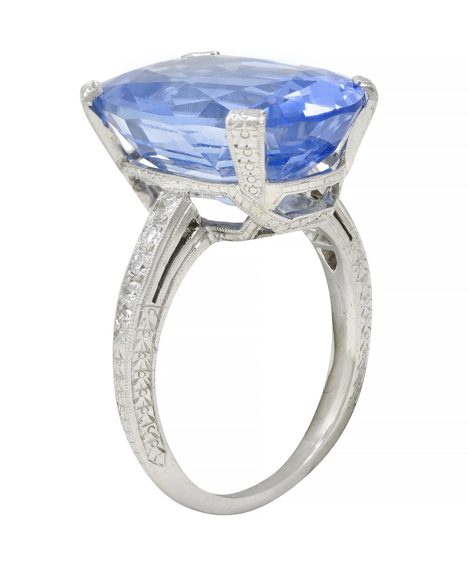Centering an oval cut sapphire weighing 15.28 carats total - transparent medium blue in color
Natural Sri Lankan in origin with no indications of heat treatment
Prong set in an ornately engraved orange blossom motif basket 
Flanked by cathedral