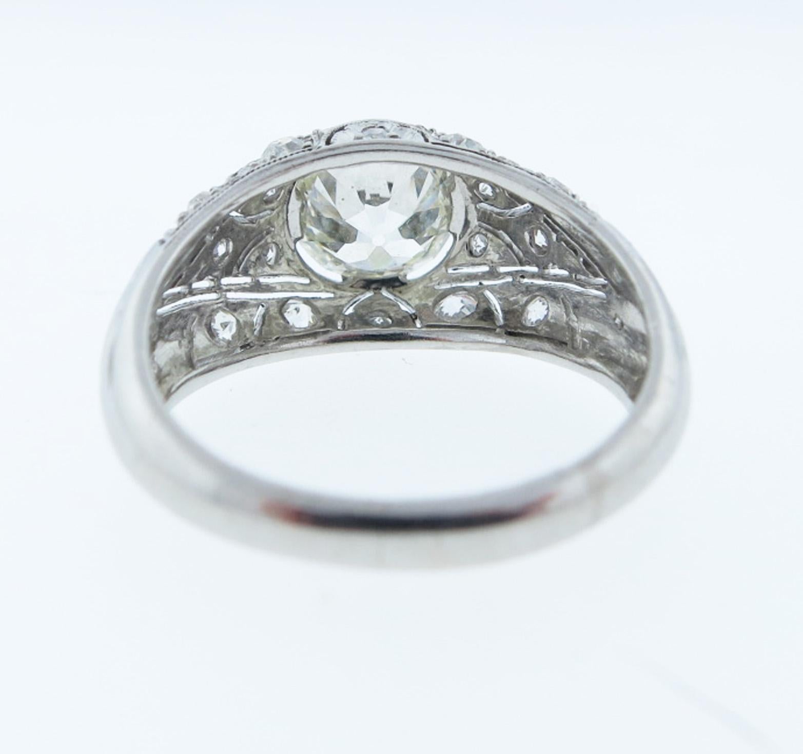 Beautiful Art Deco handmade platinum mount diamond ring, the center is bezel set with a round old European cut diamond weighing approx. 1.55 cts. grading VS clarity J color. The pierced work mount is bead set with 16 European cut diamonds totaling