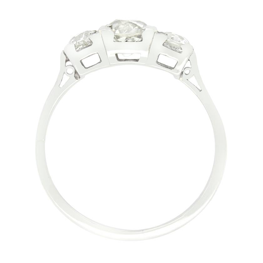 Cette bague de fiançailles classique Art déco à trois pierres présente un trio de magnifiques diamants de taille ancienne. Le diamant central est le plus gros, pesant 085 carats, tandis que les deux diamants latéraux pèsent 0,35 carat chacun. La
