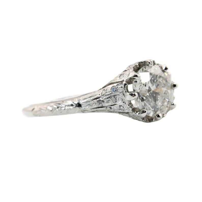 Aston Estate Jewelry Presents:

An original handmade Art Deco period diamond engagement ring in platinum. Centered by a vibrant 1.31 carat antique European cut diamond of I1 clarity, and H color. The mounting boasts 0.24 carats of pave set accent