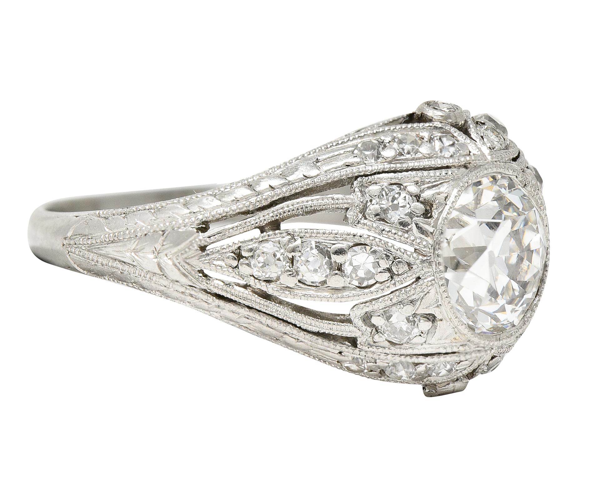 Bombè style ring is pierced in a stylized design with hand engraved foliate. Featuring an old European cut diamond weighing 1.11 carats - I color with VS1 clarity. Bezel set and surrounded by single and old European cut diamond accents. Weighing