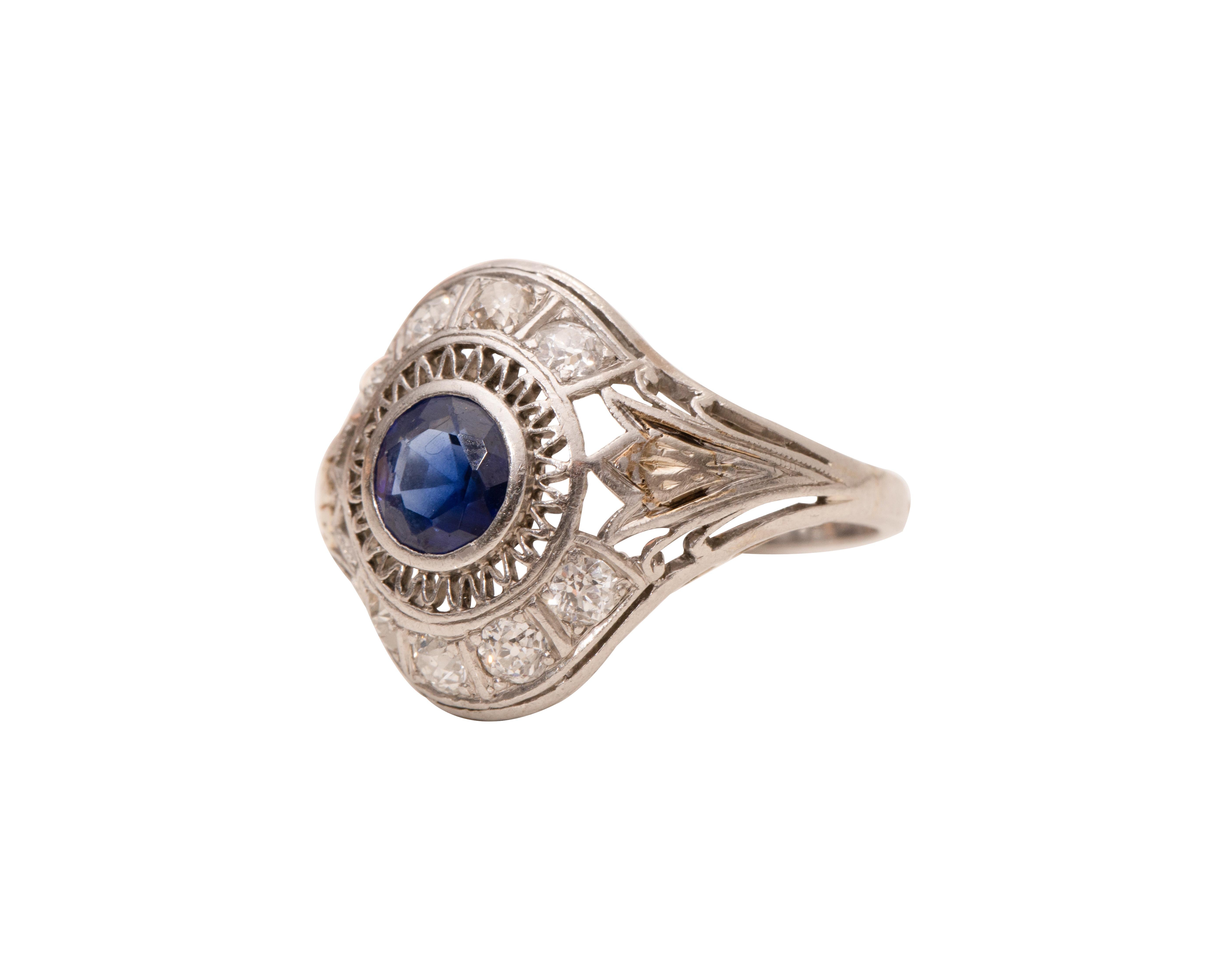 Here we have a stunning diamond and sapphire Art Deco era cocktail ring. The Platinum band has an intricate filigree and an etched design that accents the diamonds and deep blue sapphire gorgeously, taking this beauty to the next level. This classic