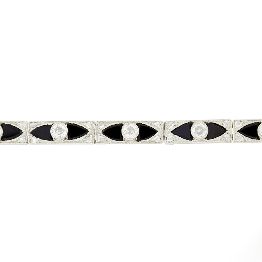 Classically Art Deco in its styling, this beautiful bracelet dates to the 1920s. Hand crafted in platinum, the bracelet features a collection of deep black onyx and sparkling white diamonds across its length. The fourteen rub over set diamonds total