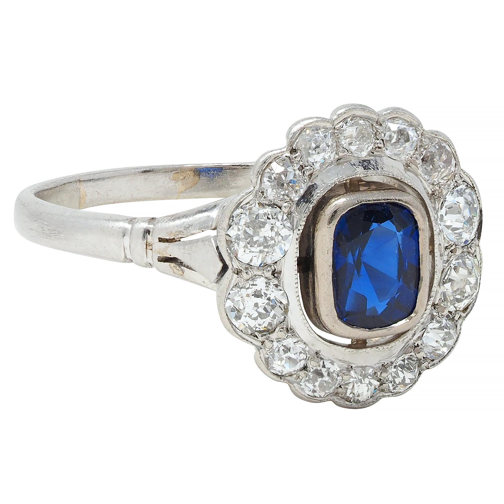 Centering a cushion cut sapphire weighing approximately 0.88 carat - transparent medium blue
Bezel set with a pierced floating halo surround of old European cut diamonds
Weighing approximately 0.74 carat total - G/H color with VS2 clarity
Bead set