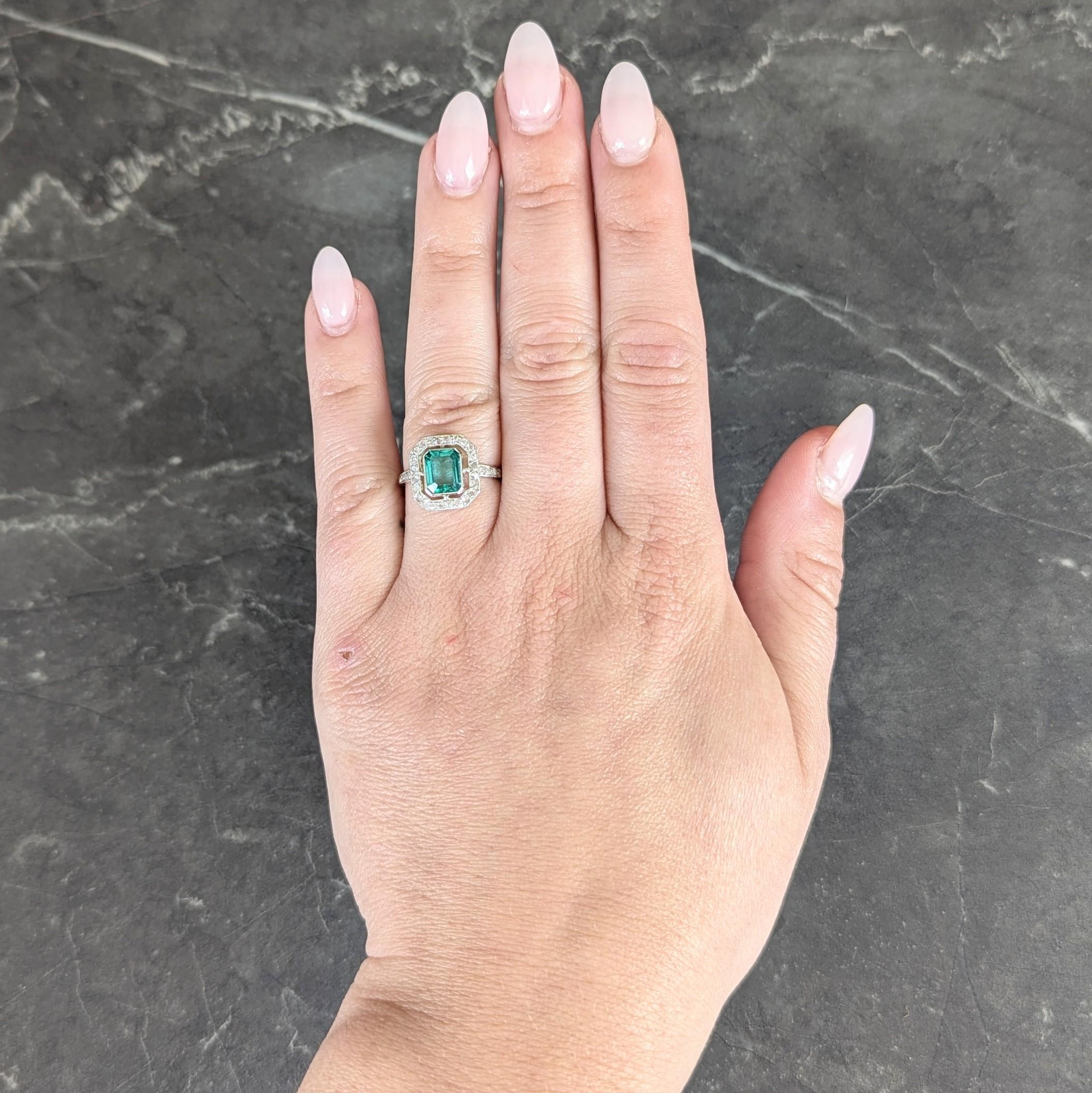 Centering an emerald cut emerald weighing approximately 1.47 carats total - transparent medium green
Natural Colombian in origin and displaying moderate clarity enhancement (F2)
Set in a platinum topped bezel with a pierced floating halo surround of