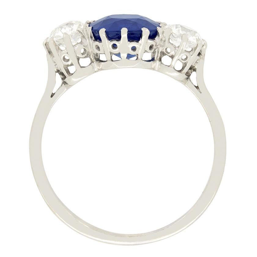 This stunning Art Deco trilogy ring features a wonderful deep blue sapphire flanked by a pair of old cut diamonds. The 1.68 carat sapphire is a completely natural and unheated cushion cut stone. The two flanking diamonds are 0.30 carat a piece. The
